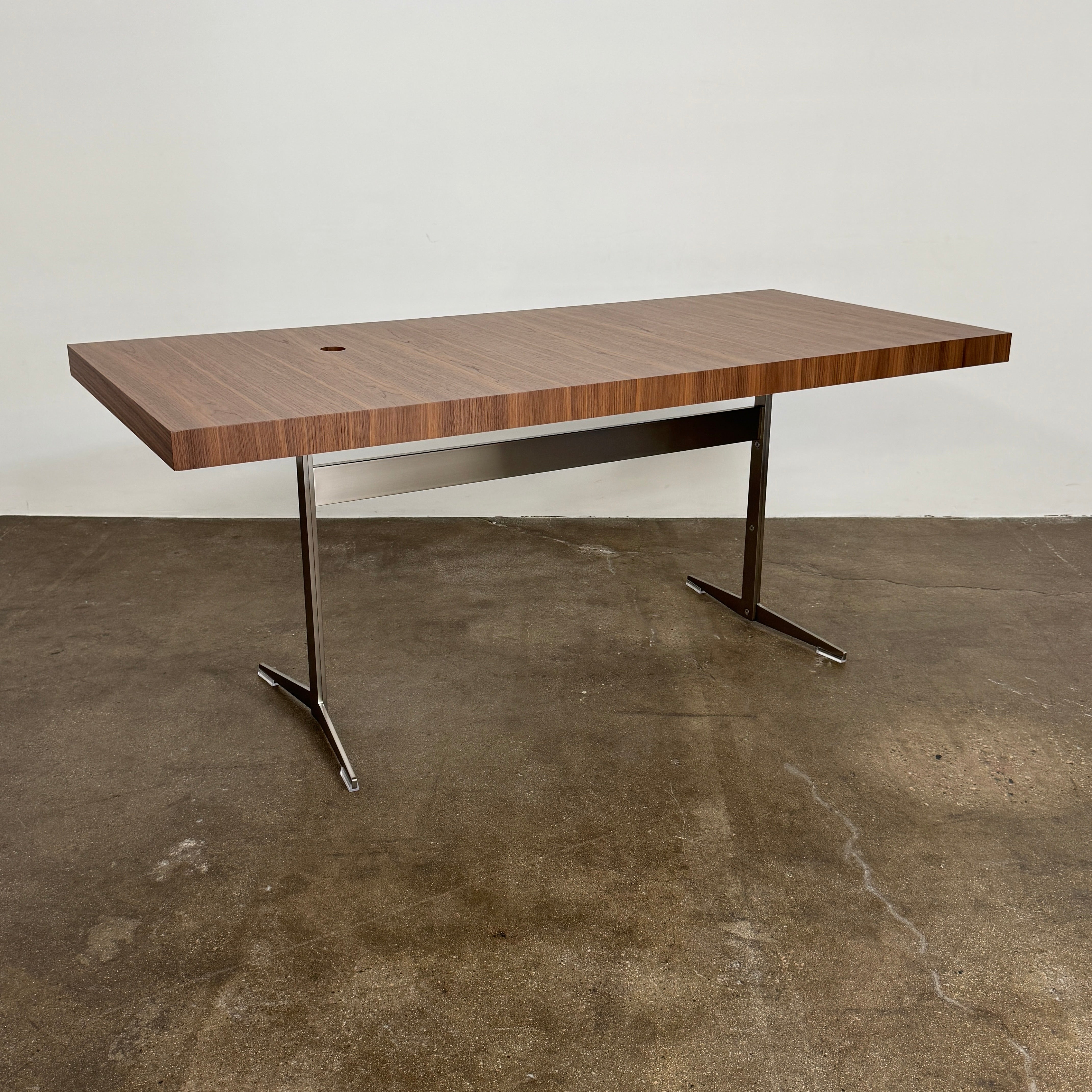 The Flexform Fly Canaletto Walnut Desk is a custom wood desk with a central circular cable management hole, reflecting the refined style of Flexform.