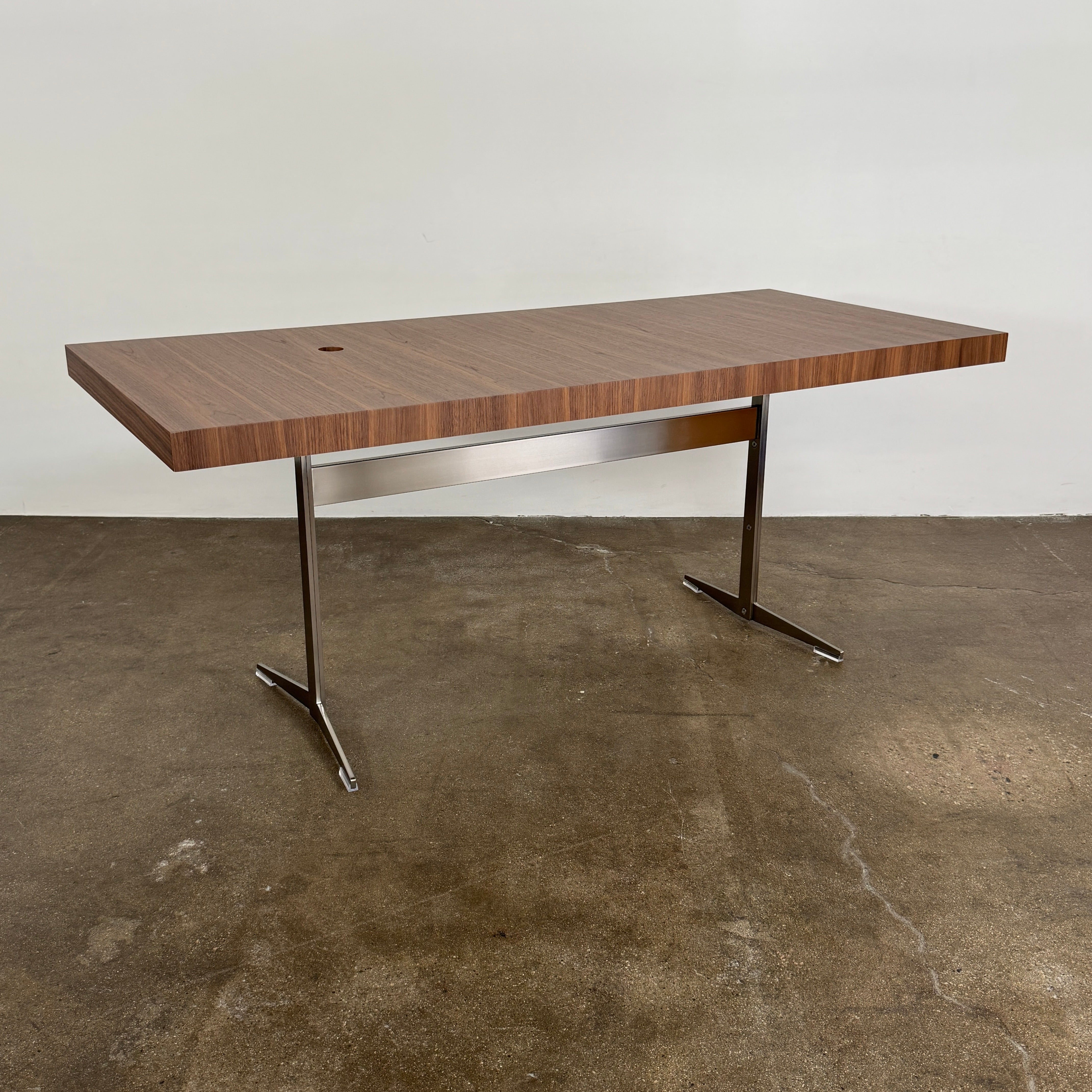 The Flexform Fly Canaletto Walnut Desk is a custom wood desk with a central circular cable management hole, reflecting the refined style of Flexform.