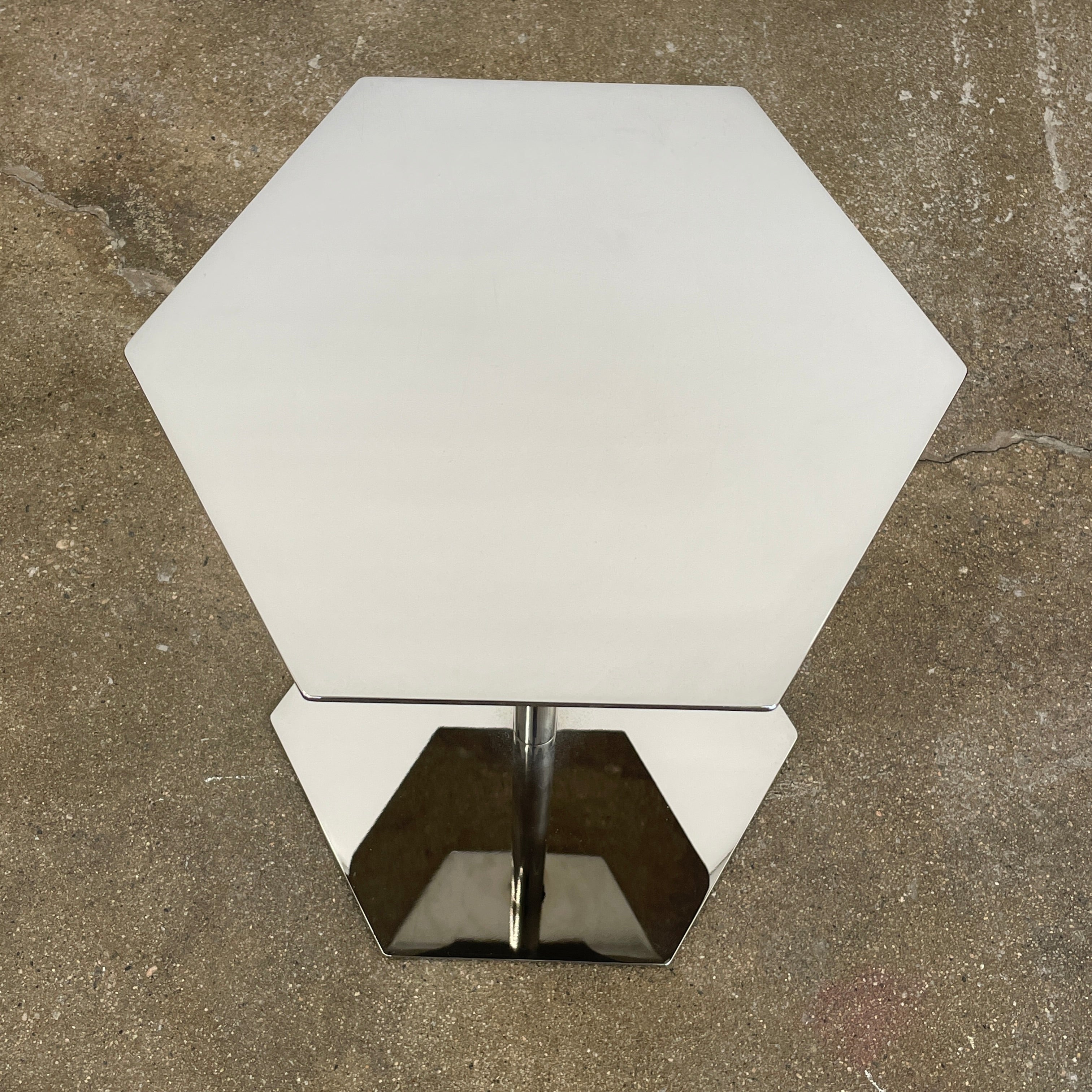 The Minotti Brisley Side Table by Rodolfo Dordoni features a stylish hexagonal metal surface supported by a central stand that flows into a matching base.