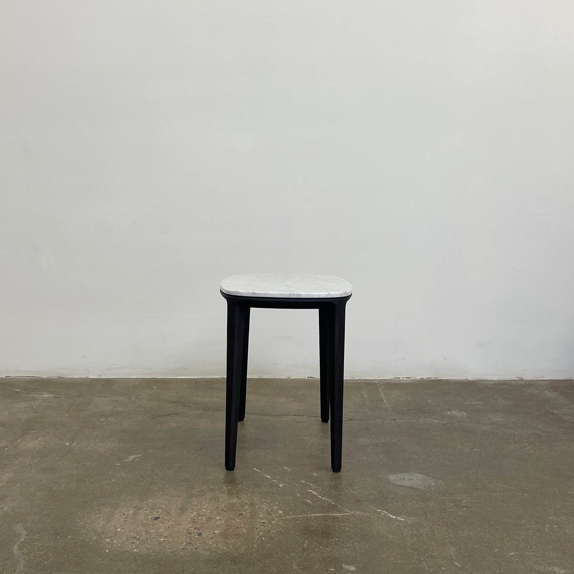 The Poliform Henry Marble Side Table, by Poliform, showcases an elegant small oval design with a luxurious Carrara marble top. It stands gracefully on four black Elm legs against a minimalist white backdrop.