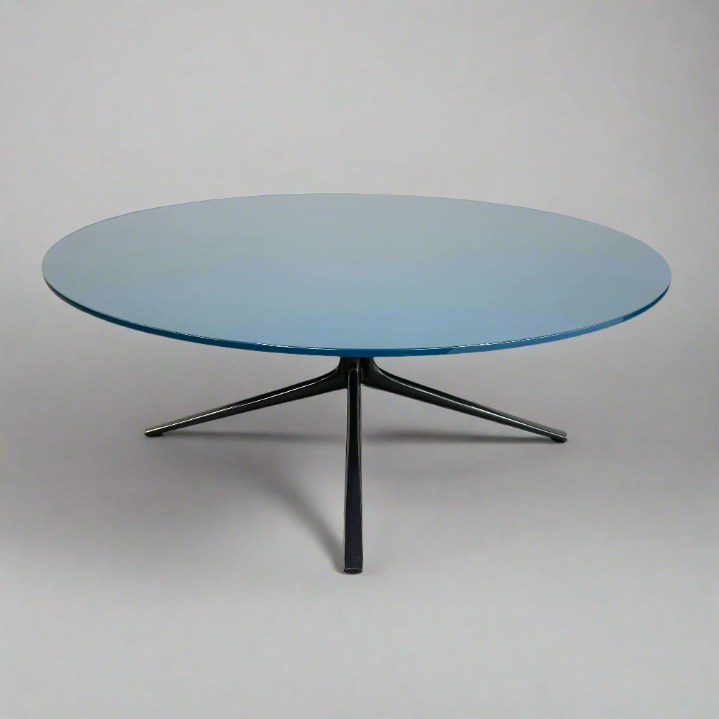 The Poliform Mondrian Lacquered Coffee Table showcases a round blue top with a black, four-legged metal base against a white background.