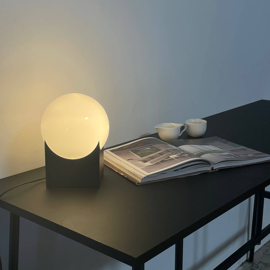 The Roll & Hill Atlas 01 Table Lamp, a white sphere on a black base, is a stunning table lamp by Roll & Hill.