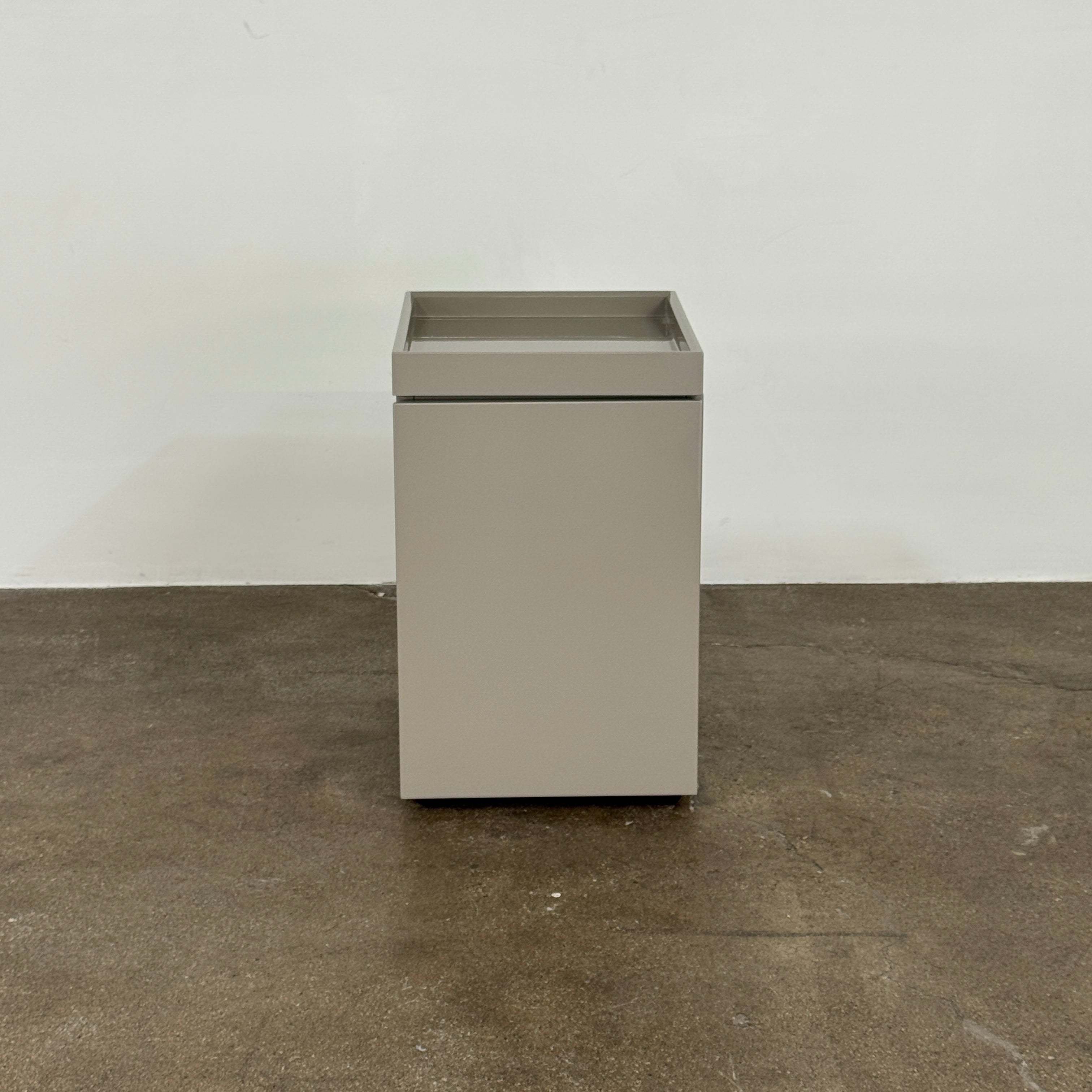 A Rev-A-Shelf instruction sheet and a "100% Thought&Made in Italy" leaflet sit on two beige trays, ideal for organizing your workspace or pairing with the Flexform Benjamin Chest of Drawers With File Insert.