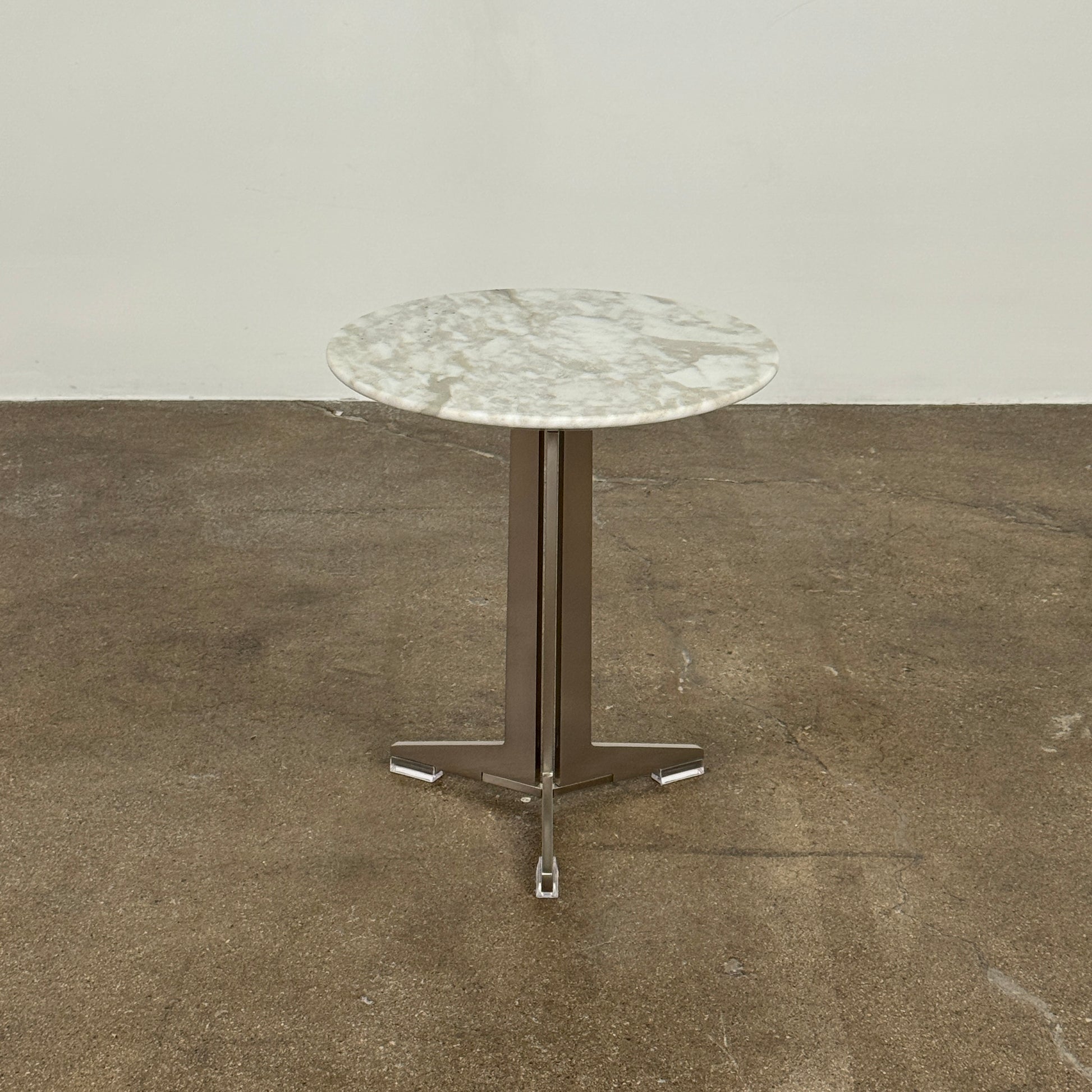 The Flexform Fly Small Table by Modern Resale is a chic side table with a white marble top and metal base, elegantly positioned on a polished concrete floor against a light-colored wall.