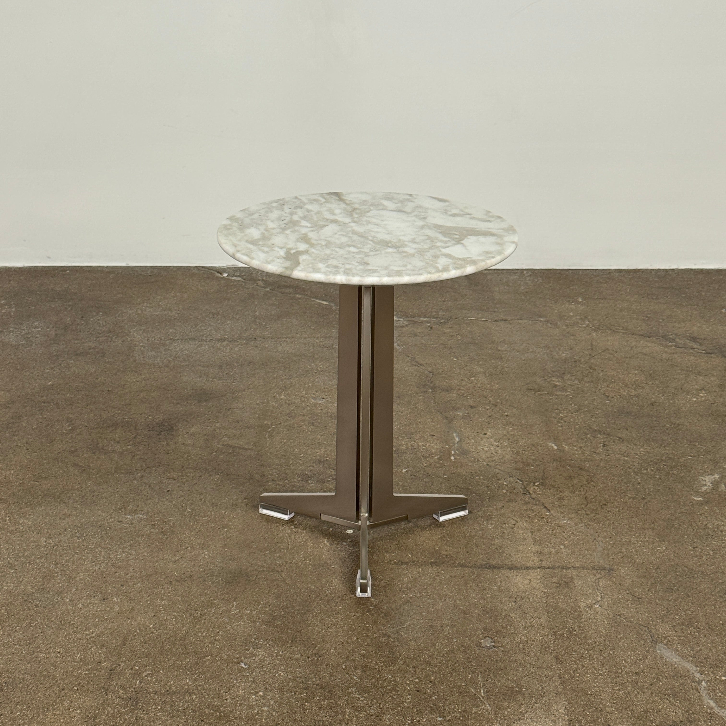 The Flexform Fly Small Table by Modern Resale is a chic side table with a white marble top and metal base, elegantly positioned on a polished concrete floor against a light-colored wall.