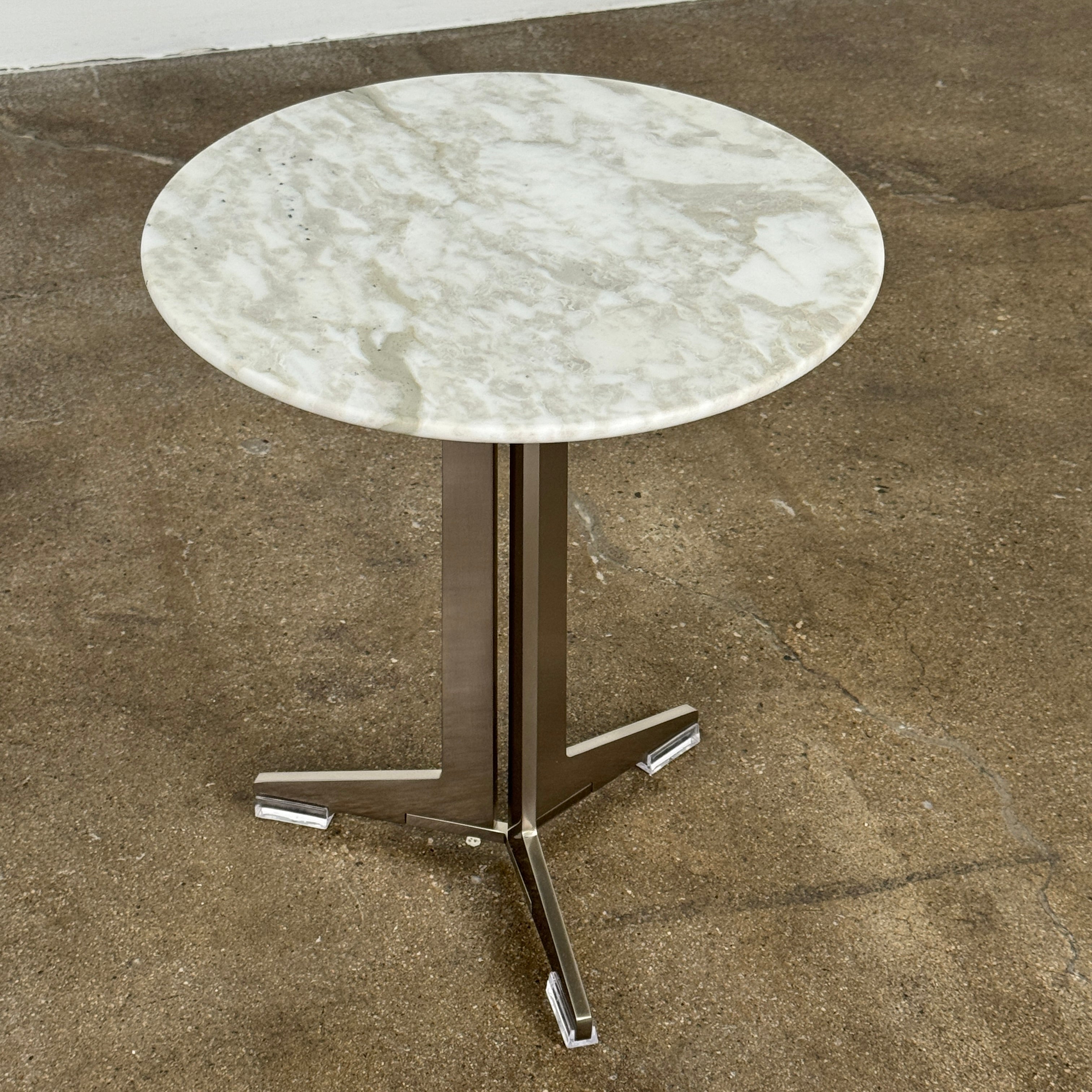 The Flexform Fly Small Table by Modern Resale is a chic side table with a white marble top and metal base, elegantly positioned on a polished concrete floor against a light-colored wall.