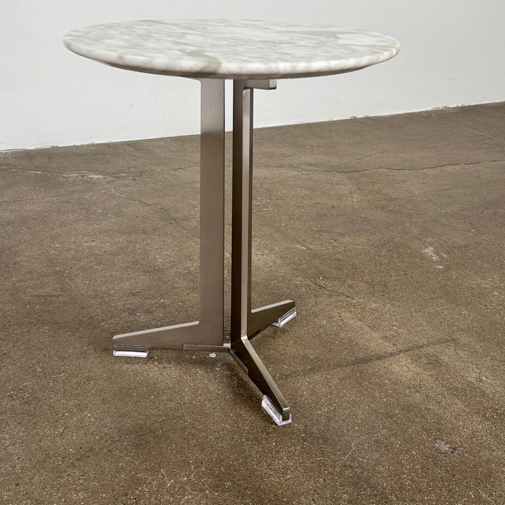 The Flexform Fly Small Table by Modern Resale is a chic side table with a white marble top and metal base, elegantly positioned on a polished concrete floor against a light-colored wall.