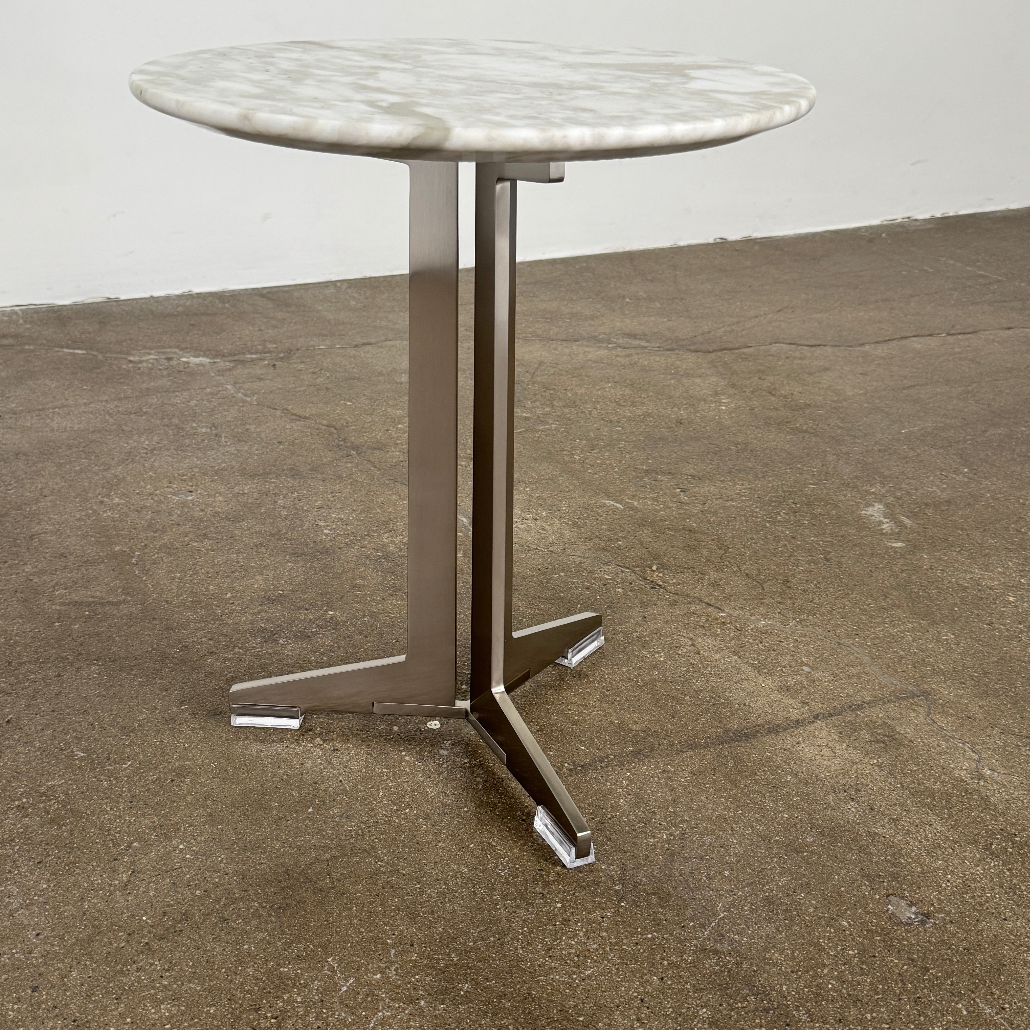 The Flexform Fly Small Table by Modern Resale is a chic side table with a white marble top and metal base, elegantly positioned on a polished concrete floor against a light-colored wall.
