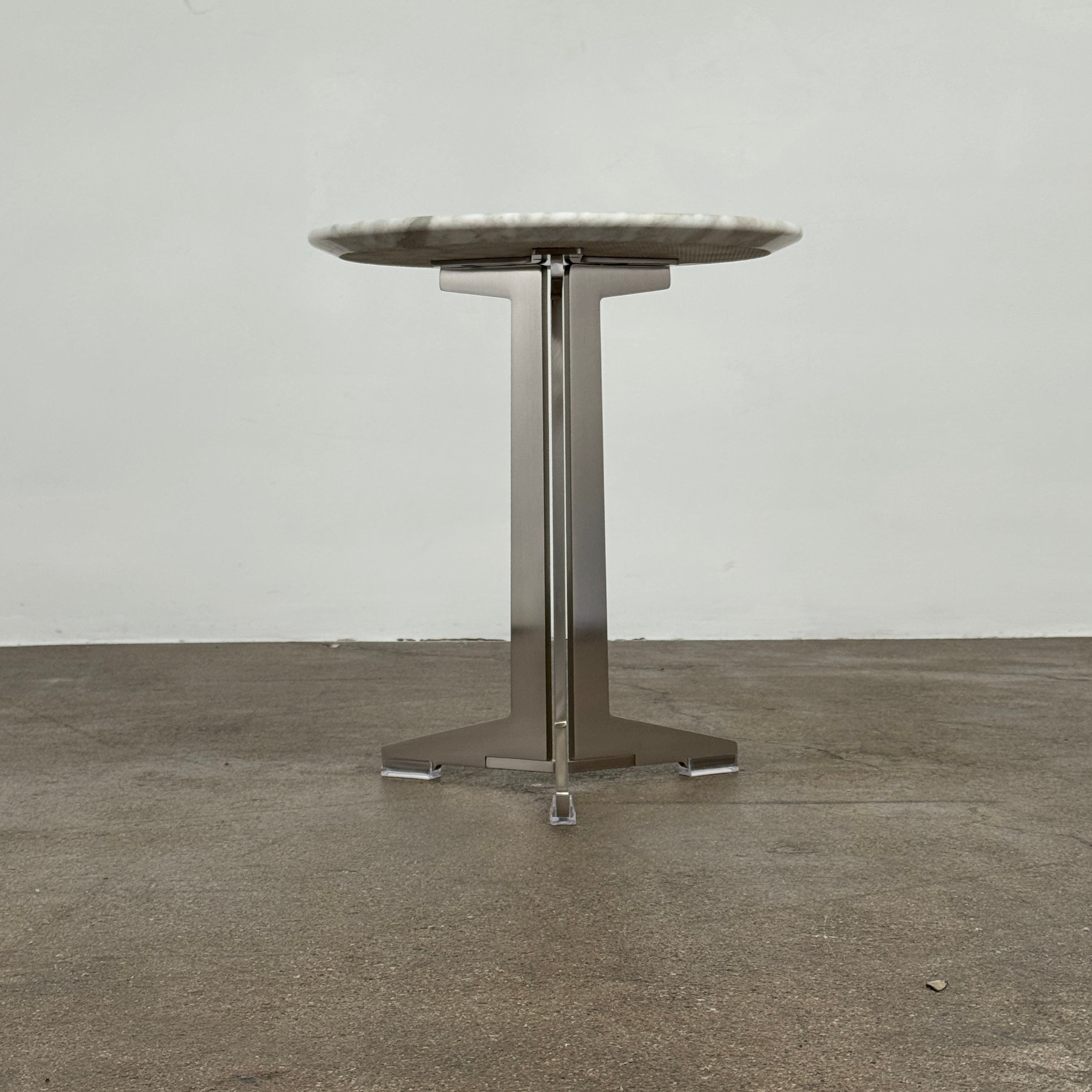 The Flexform Fly Small Table by Modern Resale is a chic side table with a white marble top and metal base, elegantly positioned on a polished concrete floor against a light-colored wall.