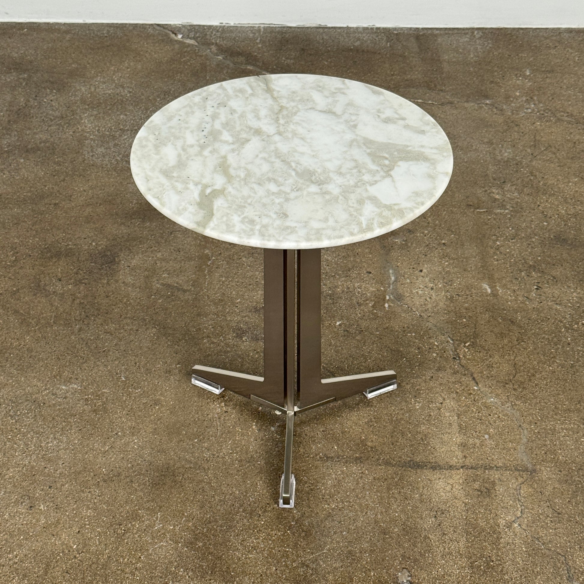 The Flexform Fly Small Table by Modern Resale is a chic side table with a white marble top and metal base, elegantly positioned on a polished concrete floor against a light-colored wall.