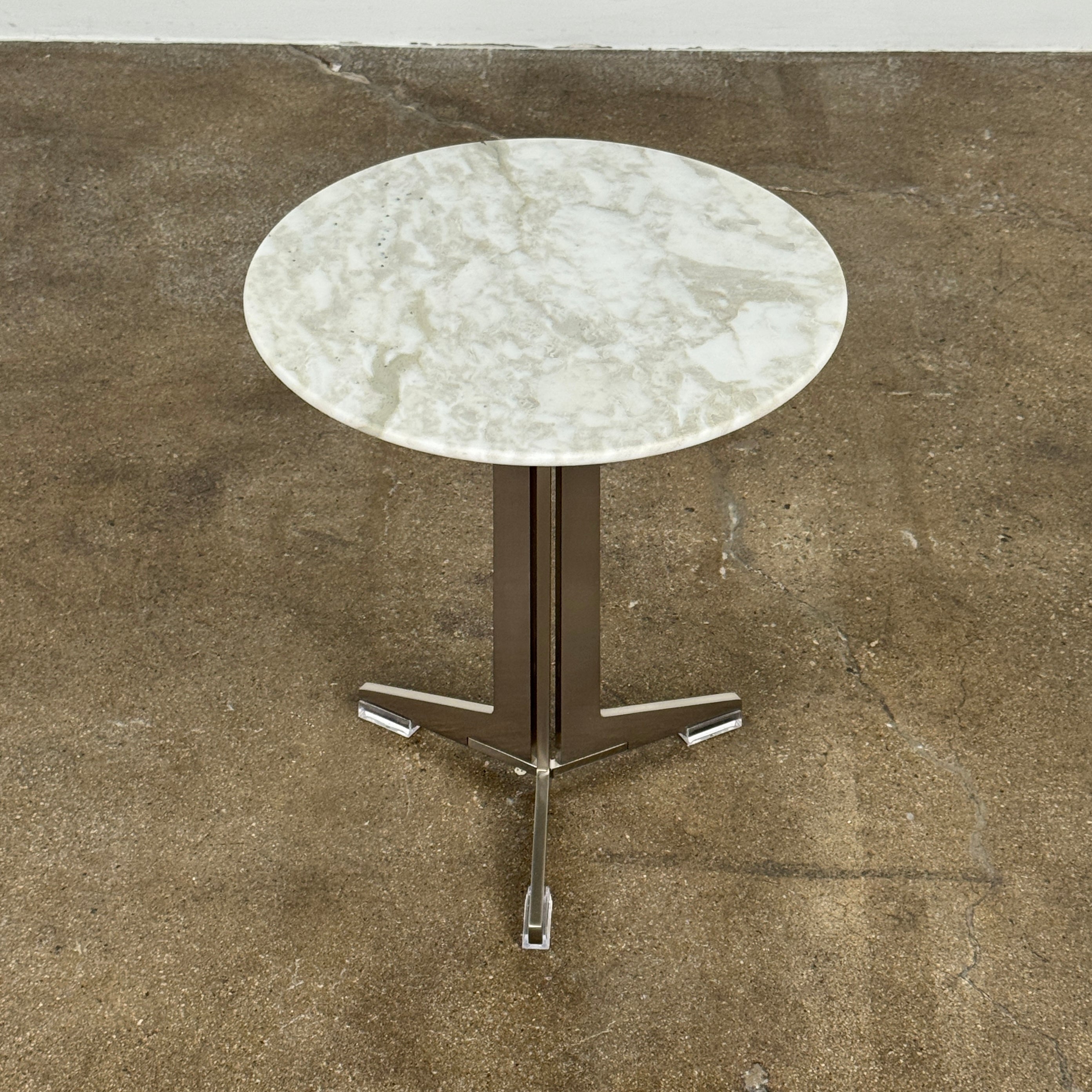 The Flexform Fly Small Table by Modern Resale is a chic side table with a white marble top and metal base, elegantly positioned on a polished concrete floor against a light-colored wall.