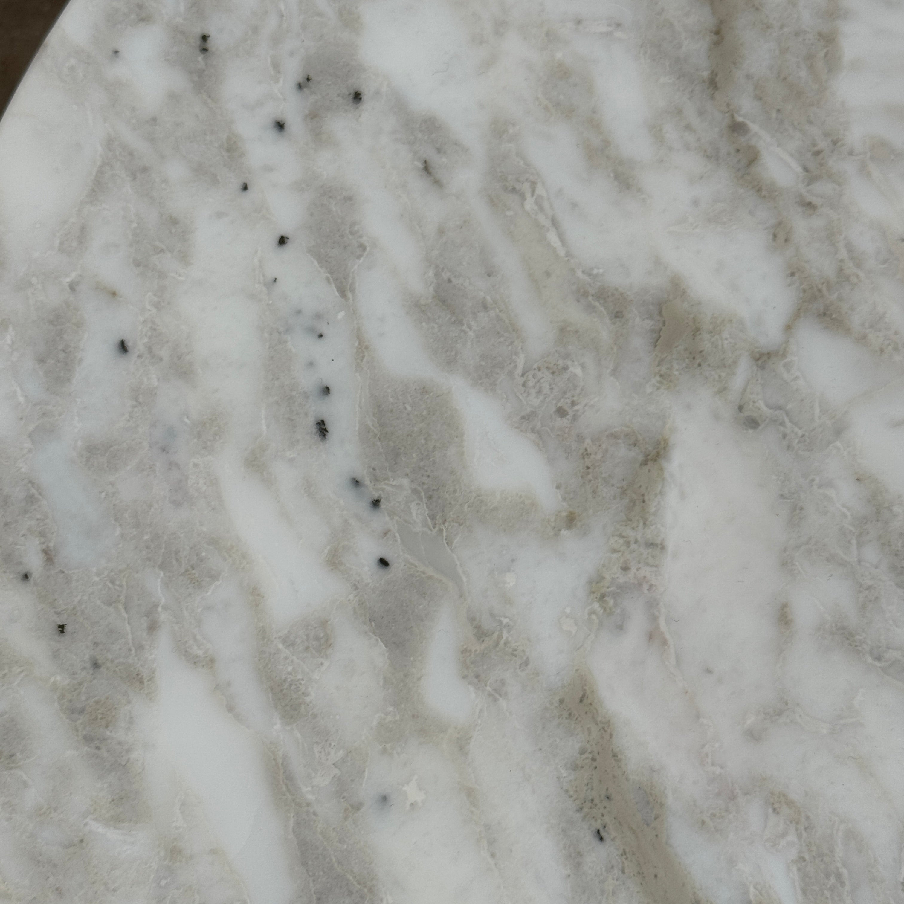 The Flexform Fly Small Table by Modern Resale is a chic side table with a white marble top and metal base, elegantly positioned on a polished concrete floor against a light-colored wall.