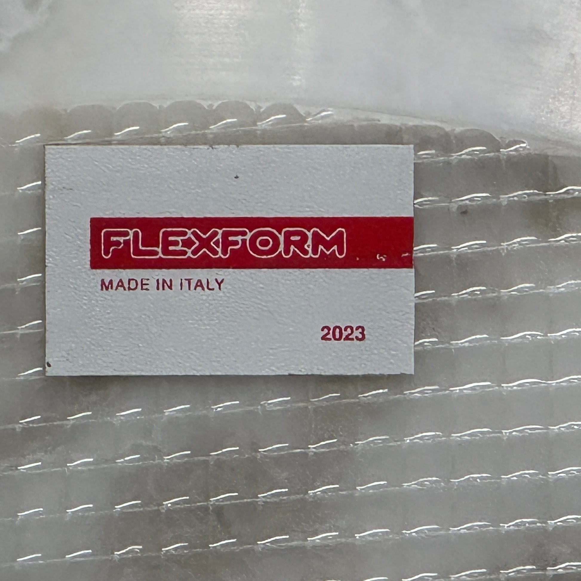 The Flexform Fly Small Table by Modern Resale is a chic side table with a white marble top and metal base, elegantly positioned on a polished concrete floor against a light-colored wall.