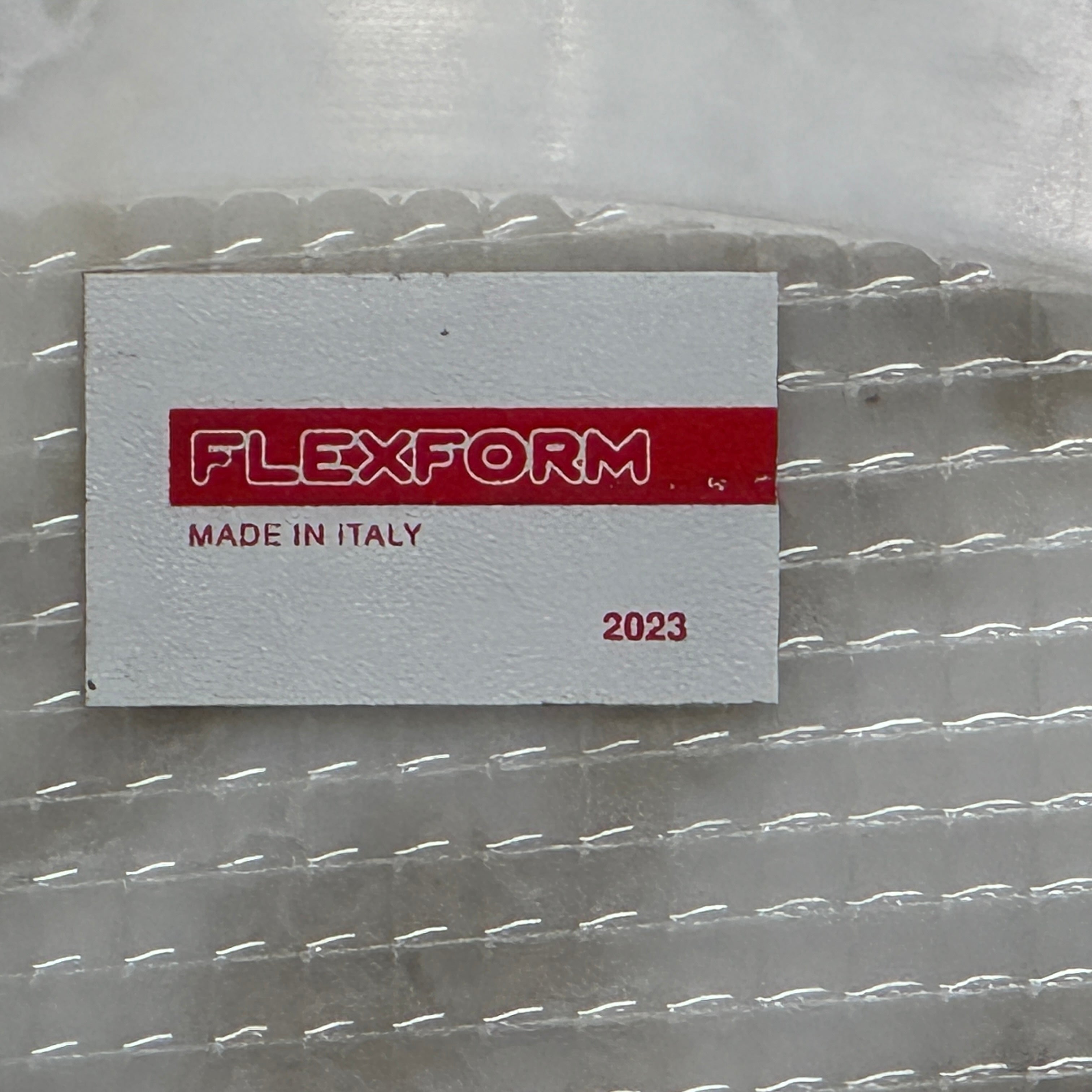 The Flexform Fly Small Table by Modern Resale is a chic side table with a white marble top and metal base, elegantly positioned on a polished concrete floor against a light-colored wall.