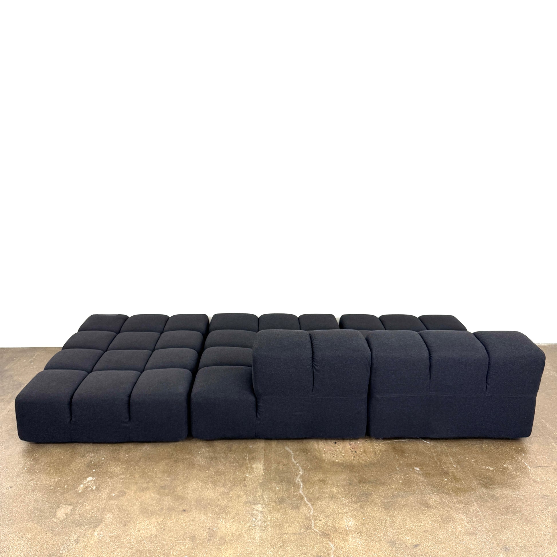 A B&B Italia 5 Piece Tufty Time Sectional with tufted cushions sits in an L-shape on a polished concrete floor against a plain white wall.