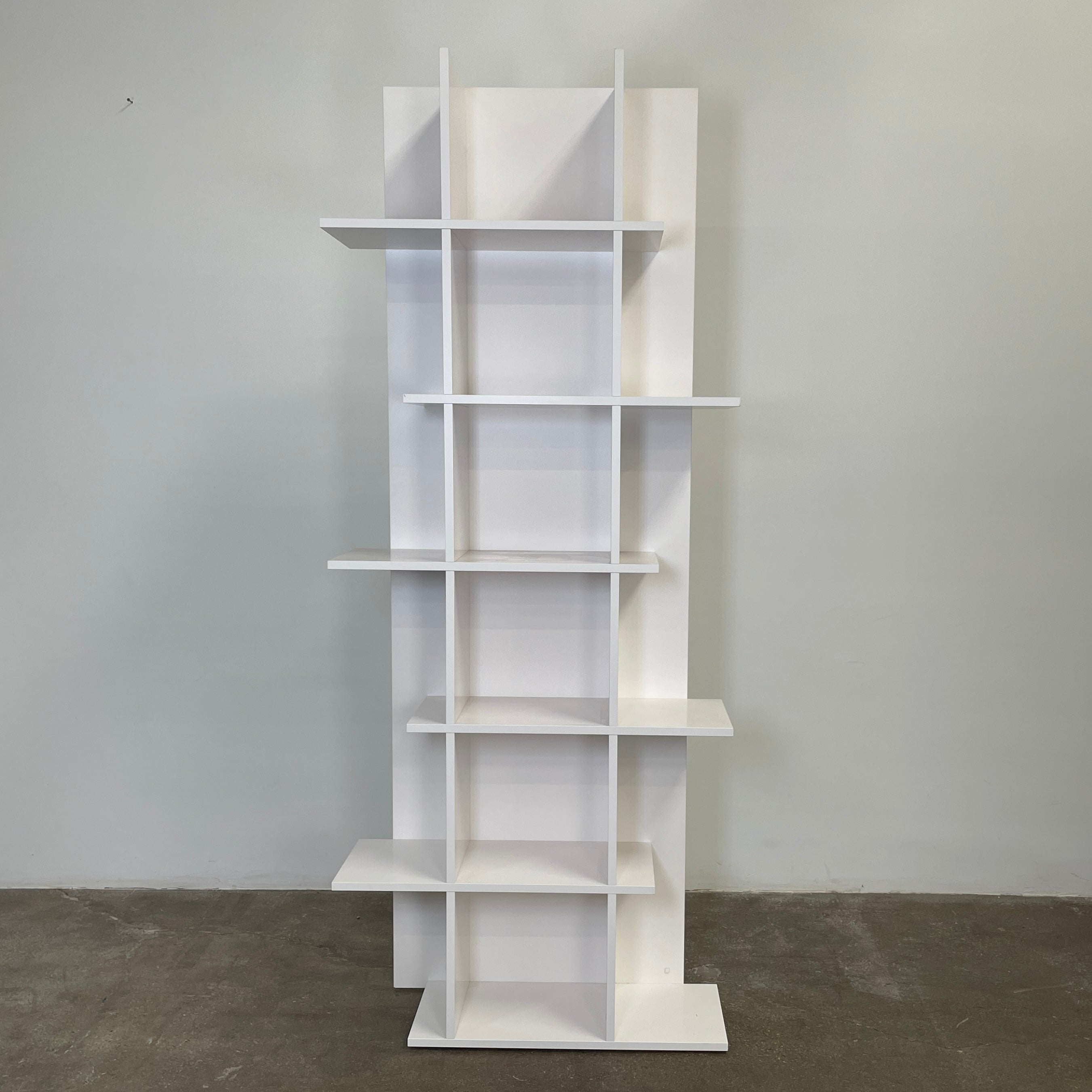 The Ligne Roset Everywhere Bookcase by Ligne Roset is a tall, modern white bookshelf with staggered geometric shelves.