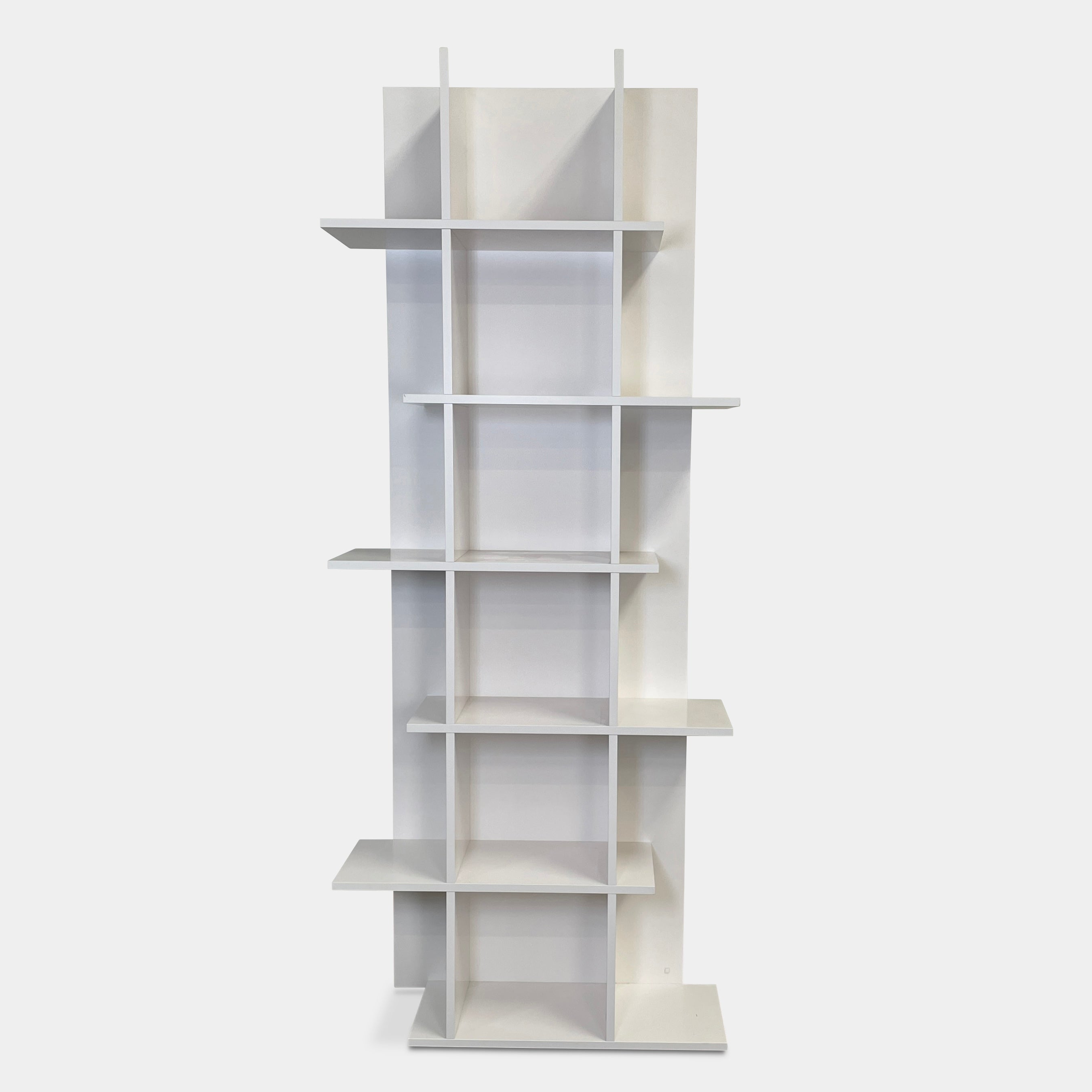 The Ligne Roset Everywhere Bookcase by Ligne Roset is a tall, modern white bookshelf with staggered geometric shelves.