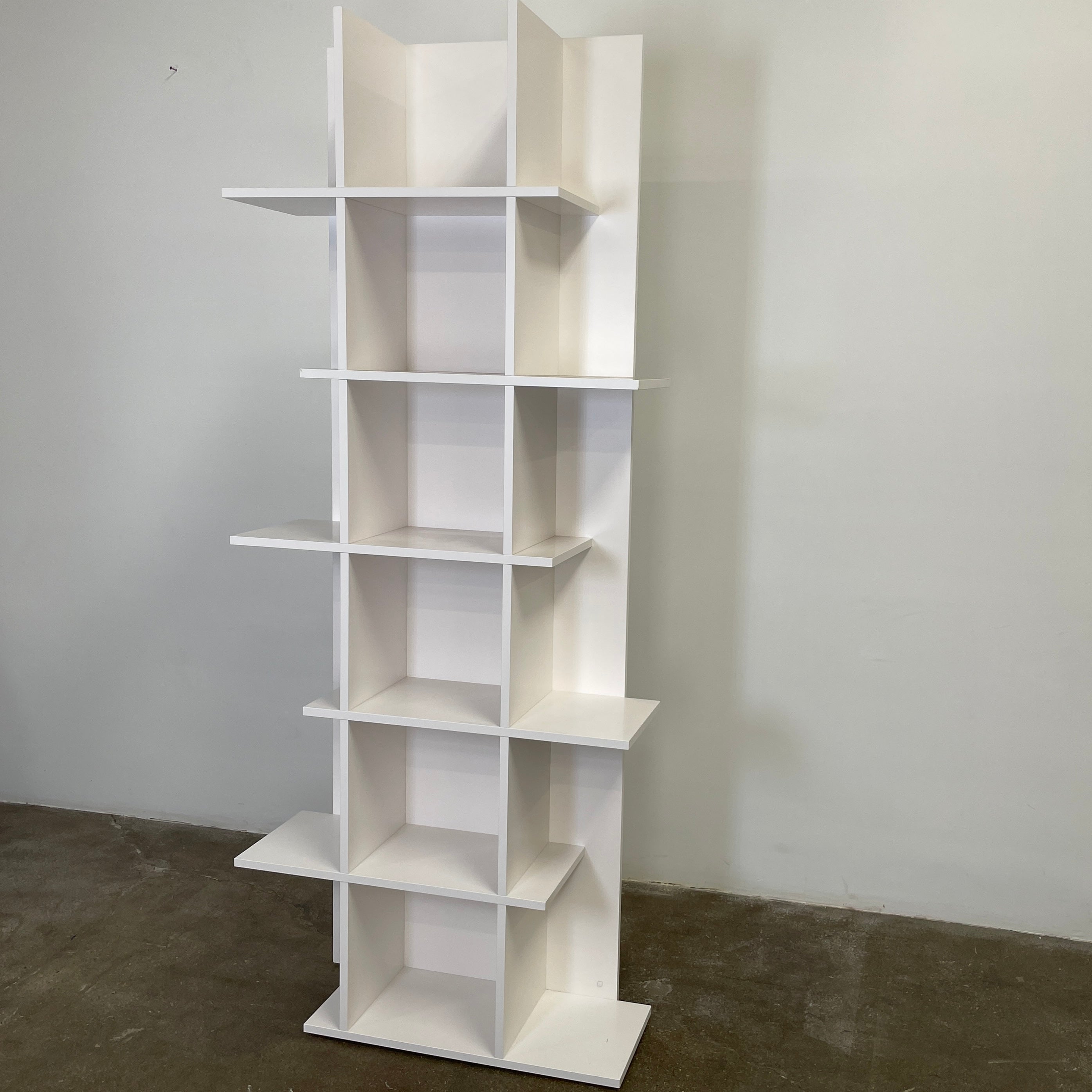 The Ligne Roset Everywhere Bookcase by Ligne Roset is a tall, modern white bookshelf with staggered geometric shelves.