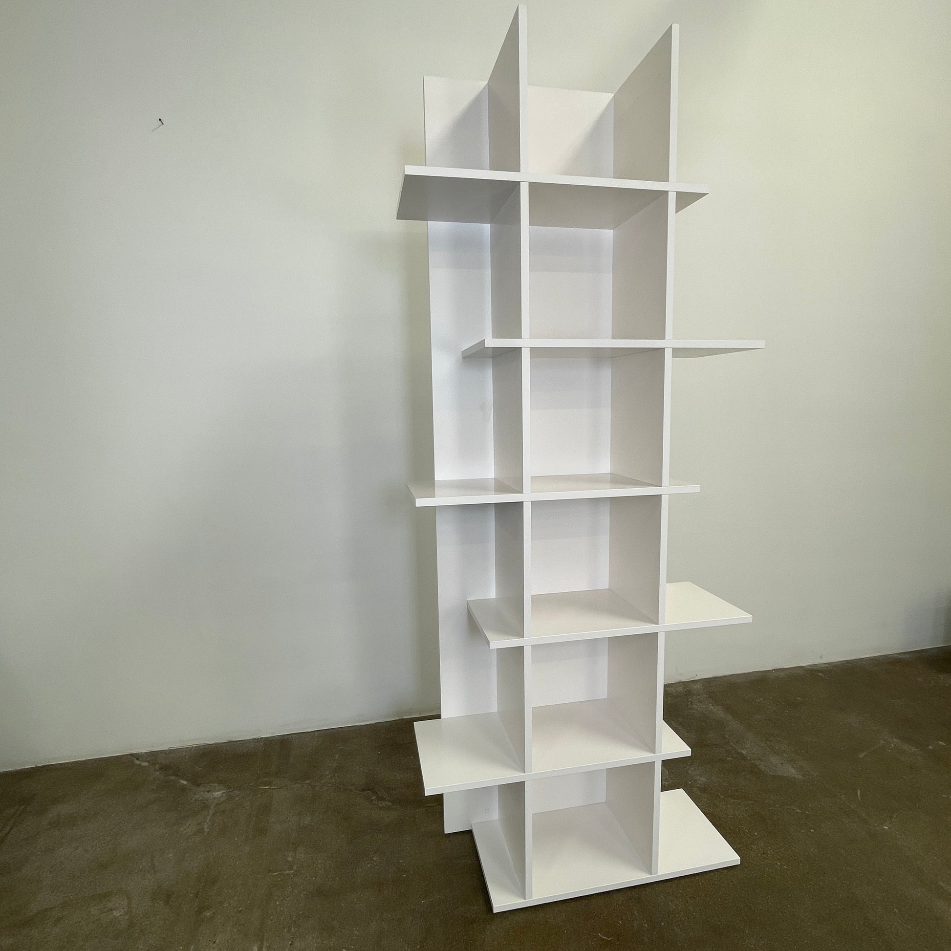 The Ligne Roset Everywhere Bookcase by Ligne Roset is a tall, modern white bookshelf with staggered geometric shelves.