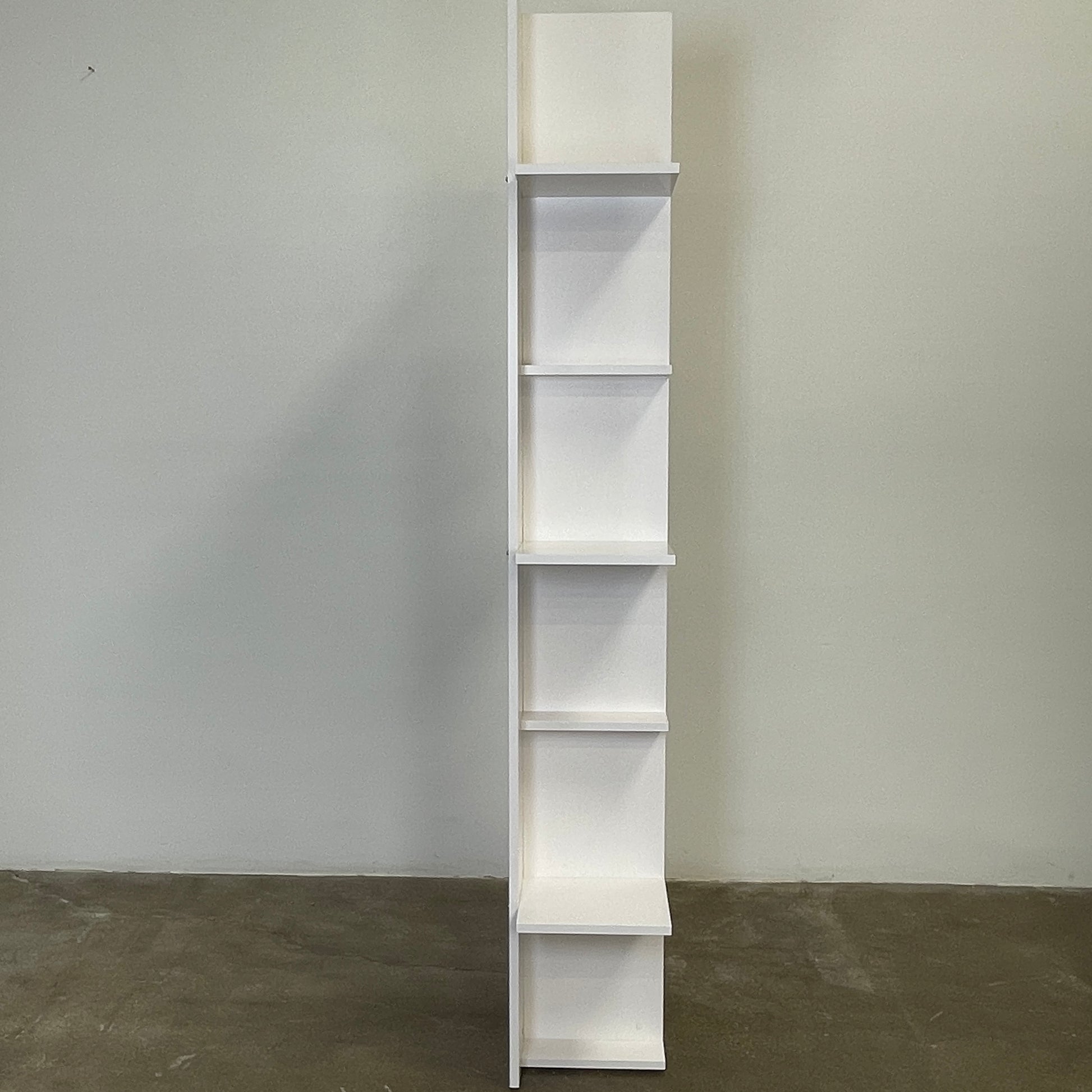 The Ligne Roset Everywhere Bookcase by Ligne Roset is a tall, modern white bookshelf with staggered geometric shelves.