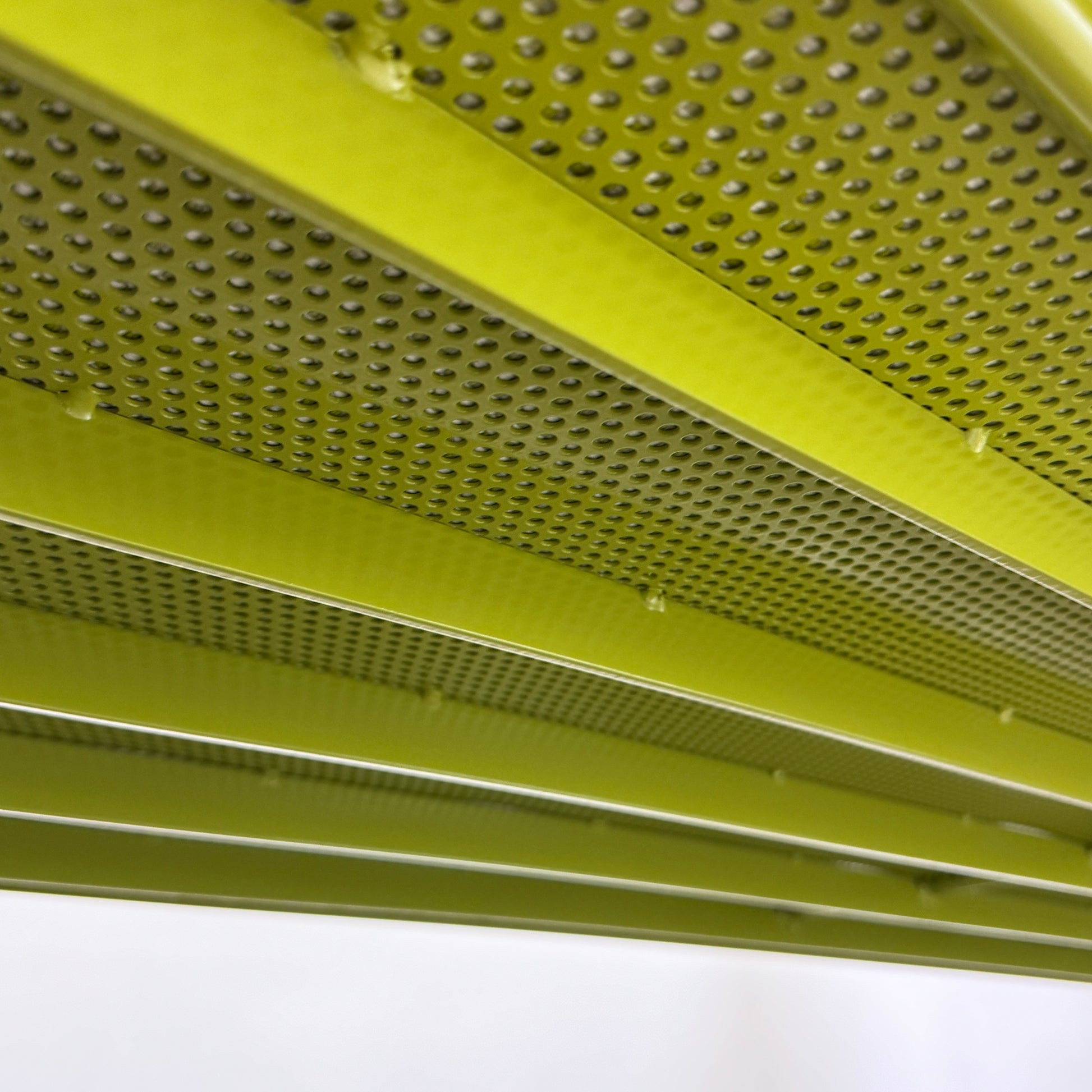 The light green Paola Lenti Kaba Outdoor Sofa by Modern Resale, featuring a metal frame, functions as a stylish two-seater and is shown against a plain white wall on a brown concrete floor.