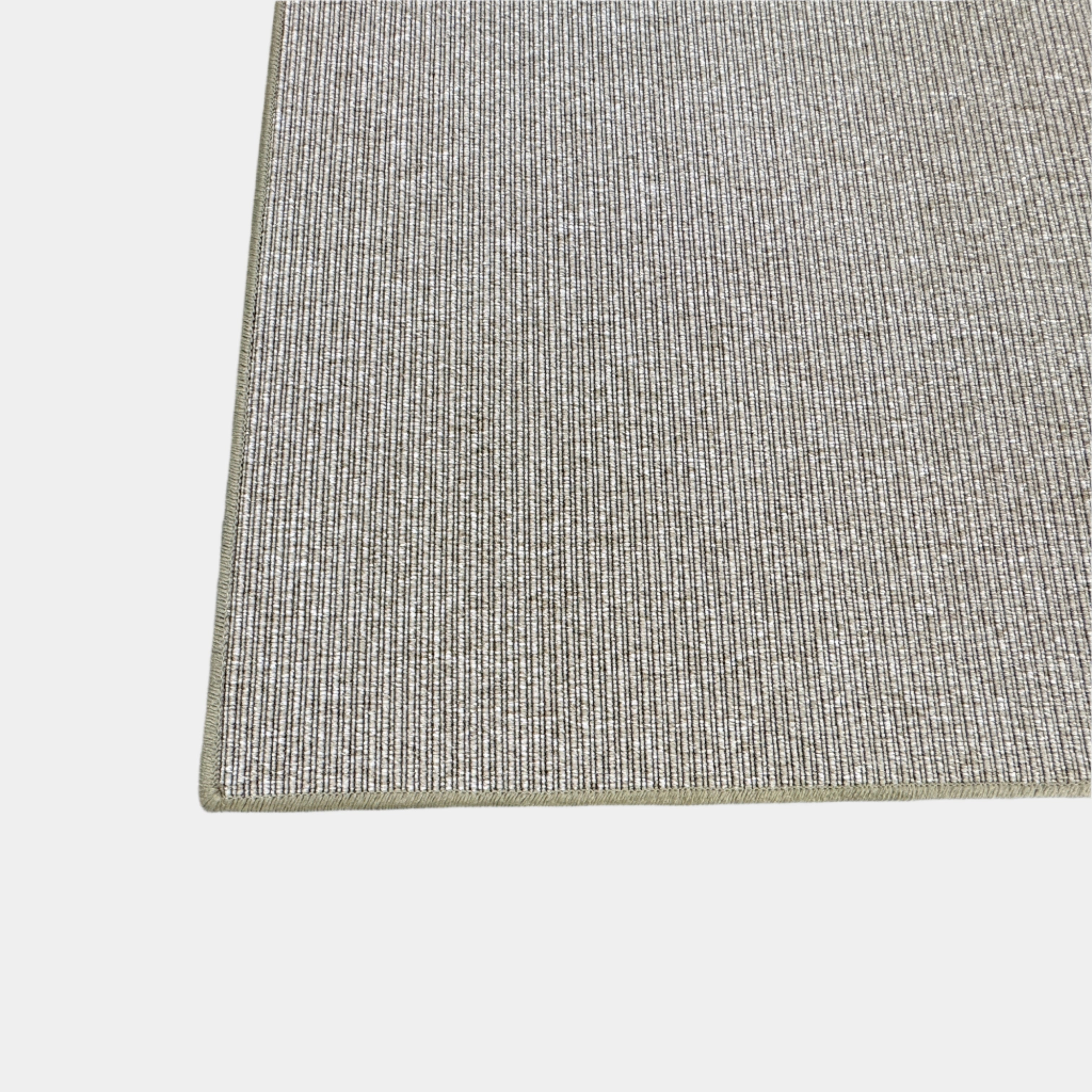 A beige Flexform Paride Rug with stitched edges rests on a polished concrete floor.