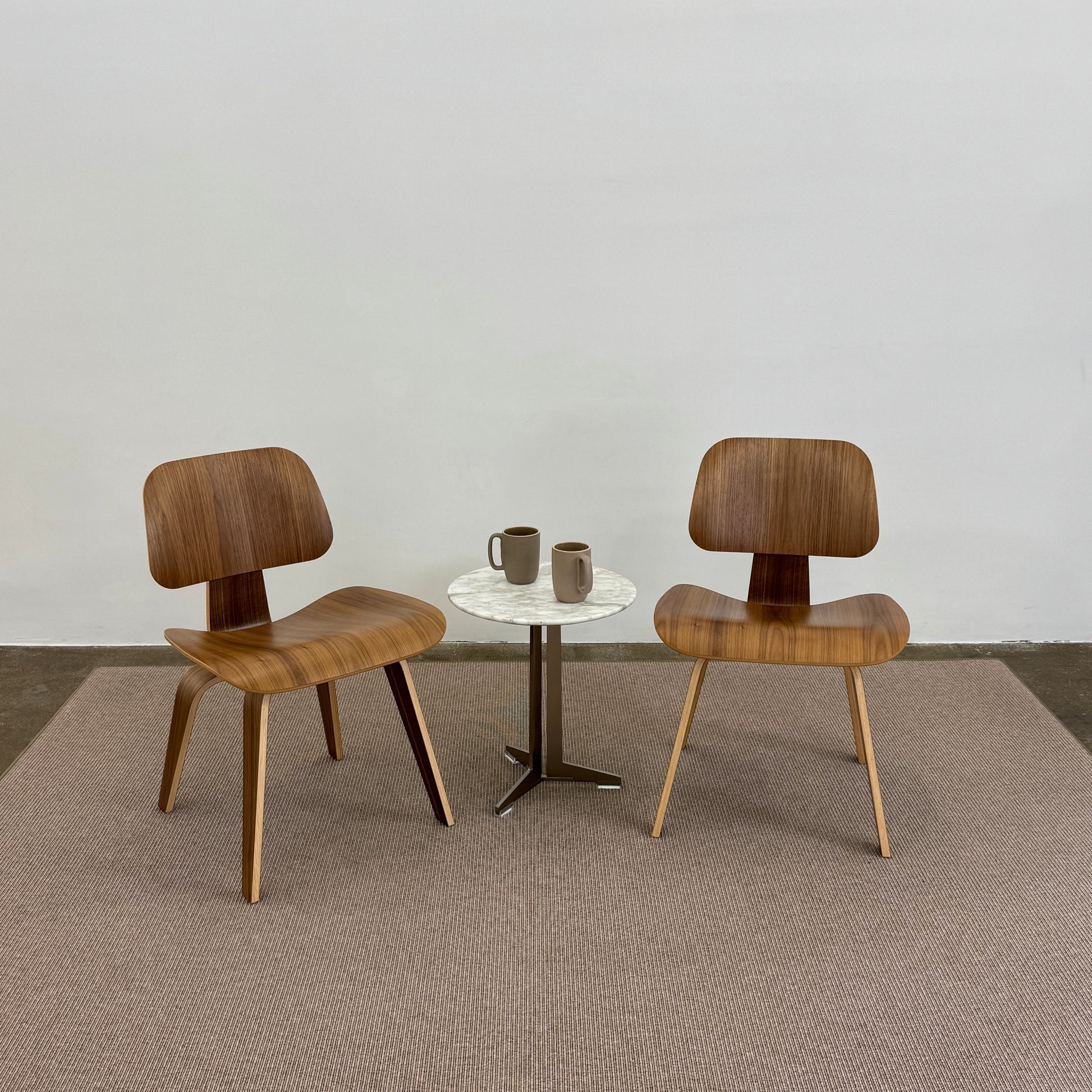 A beige Flexform Paride Rug with stitched edges rests on a polished concrete floor.