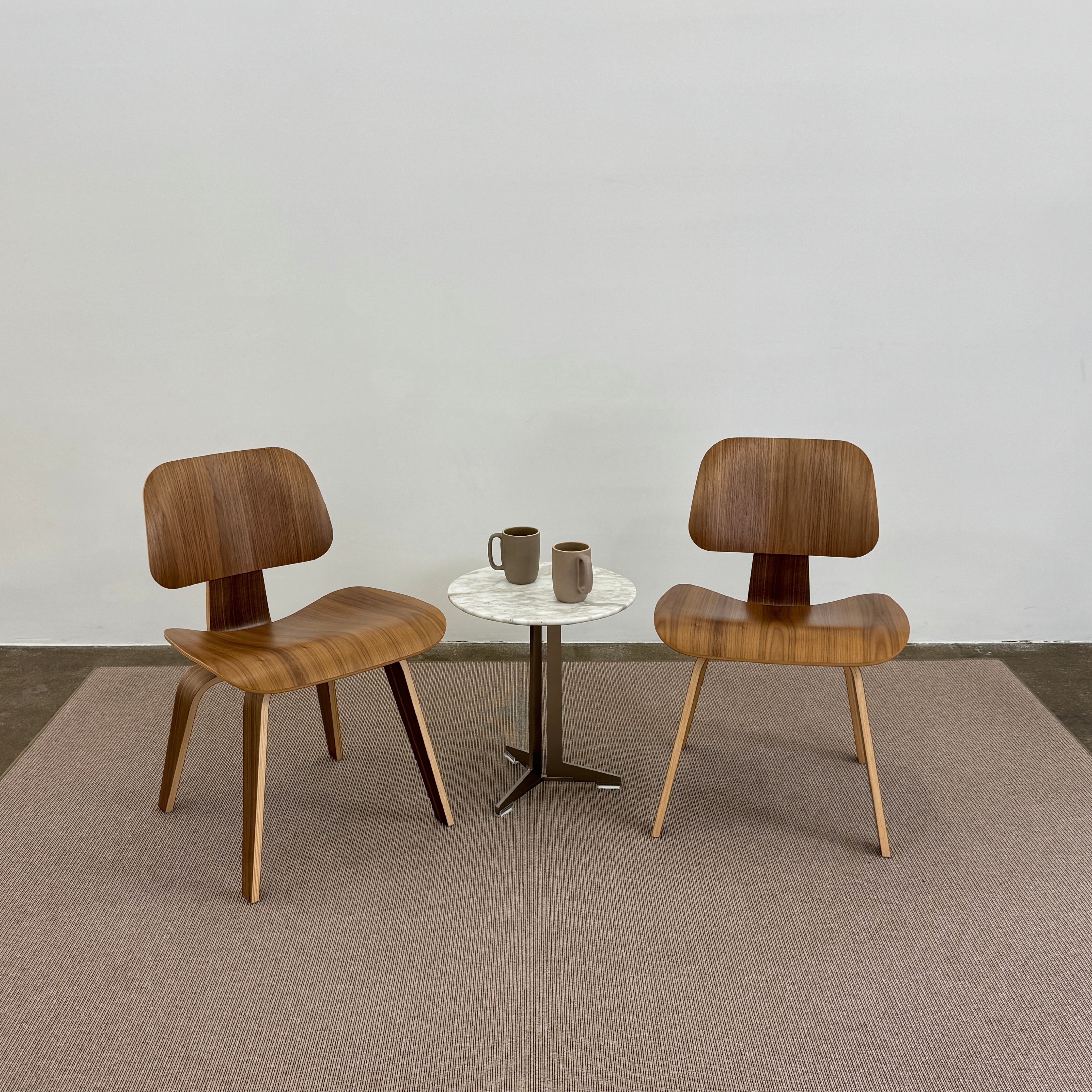 A beige Flexform Paride Rug with stitched edges rests on a polished concrete floor.