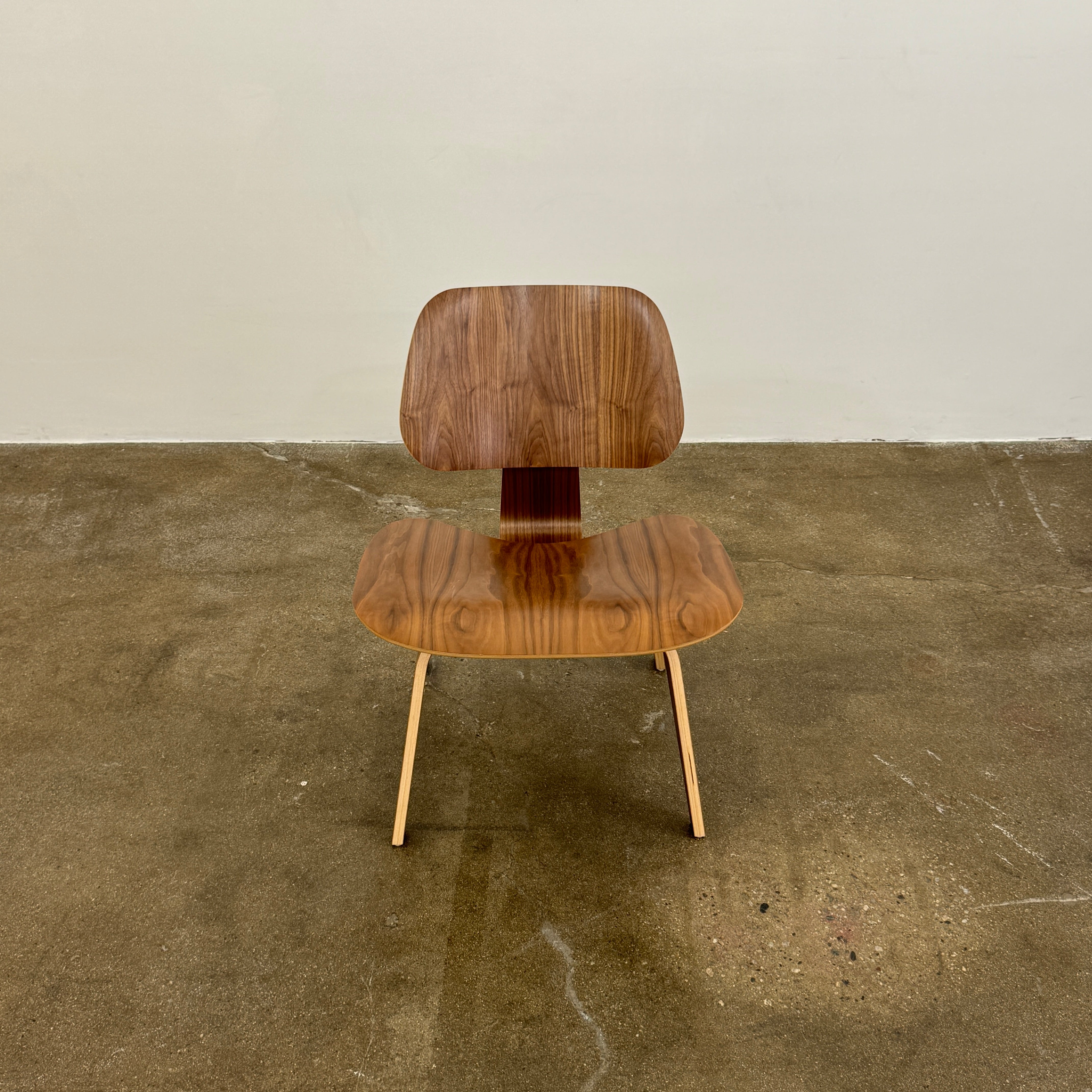 The MillerKnoll Eames Molded Plywood Lounge Chair Wood Base (LCW), featuring a curved seat, angled backrest, and splayed legs, is displayed against a plain light background.