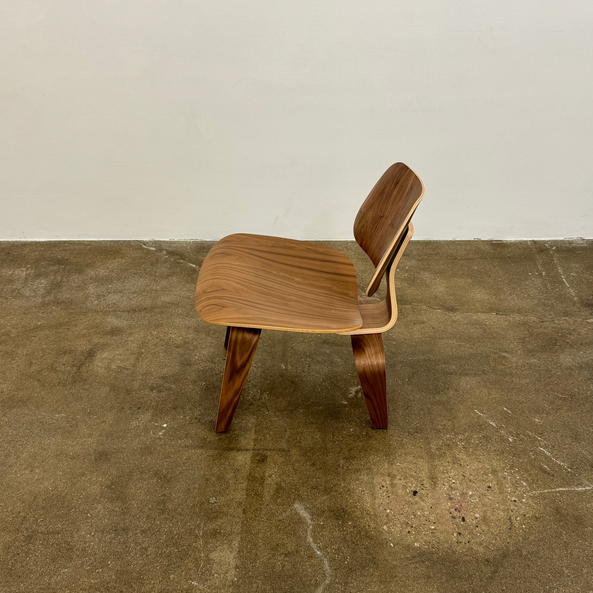 The MillerKnoll Eames Molded Plywood Lounge Chair Wood Base (LCW), featuring a curved seat, angled backrest, and splayed legs, is displayed against a plain light background.