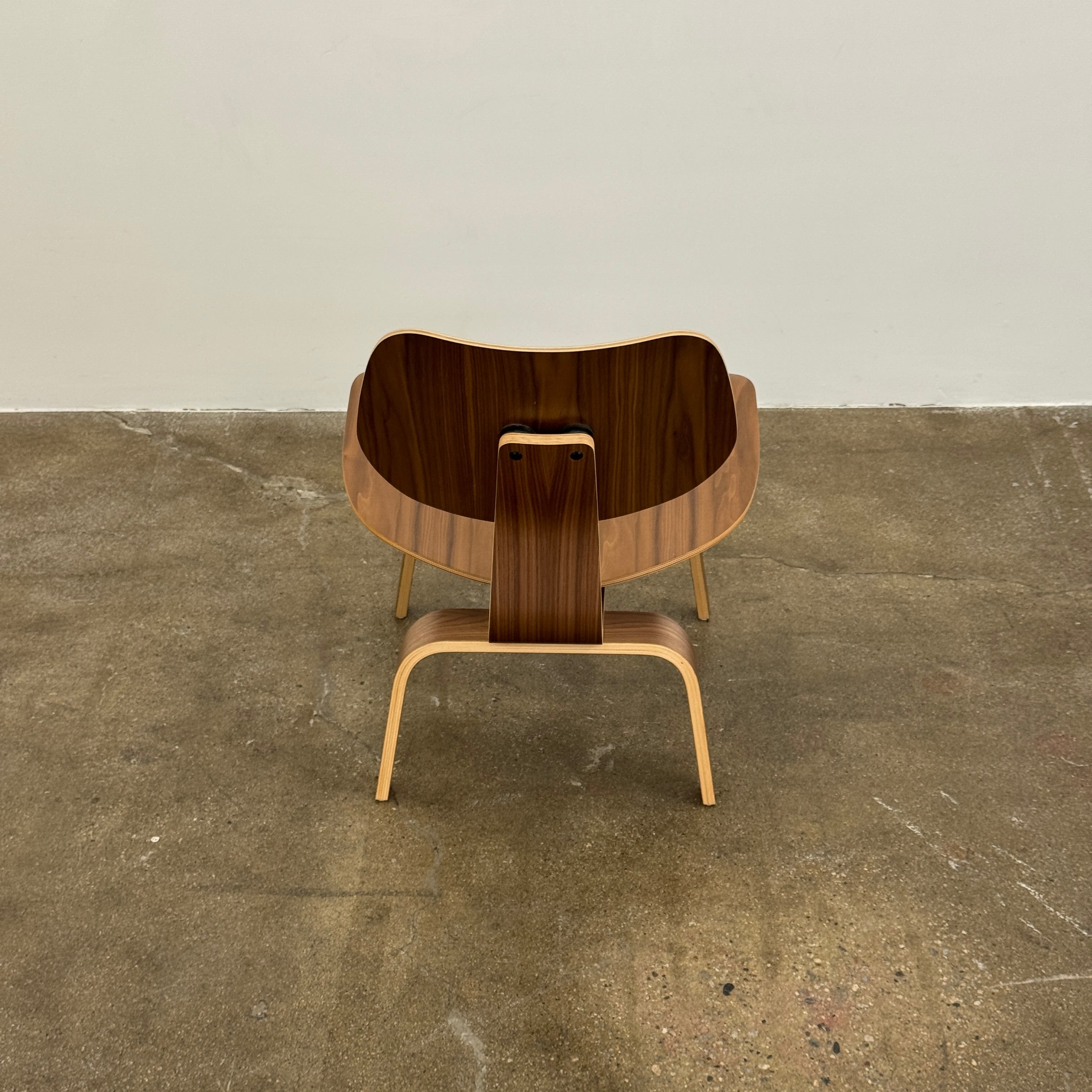The MillerKnoll Eames Molded Plywood Lounge Chair Wood Base (LCW), featuring a curved seat, angled backrest, and splayed legs, is displayed against a plain light background.