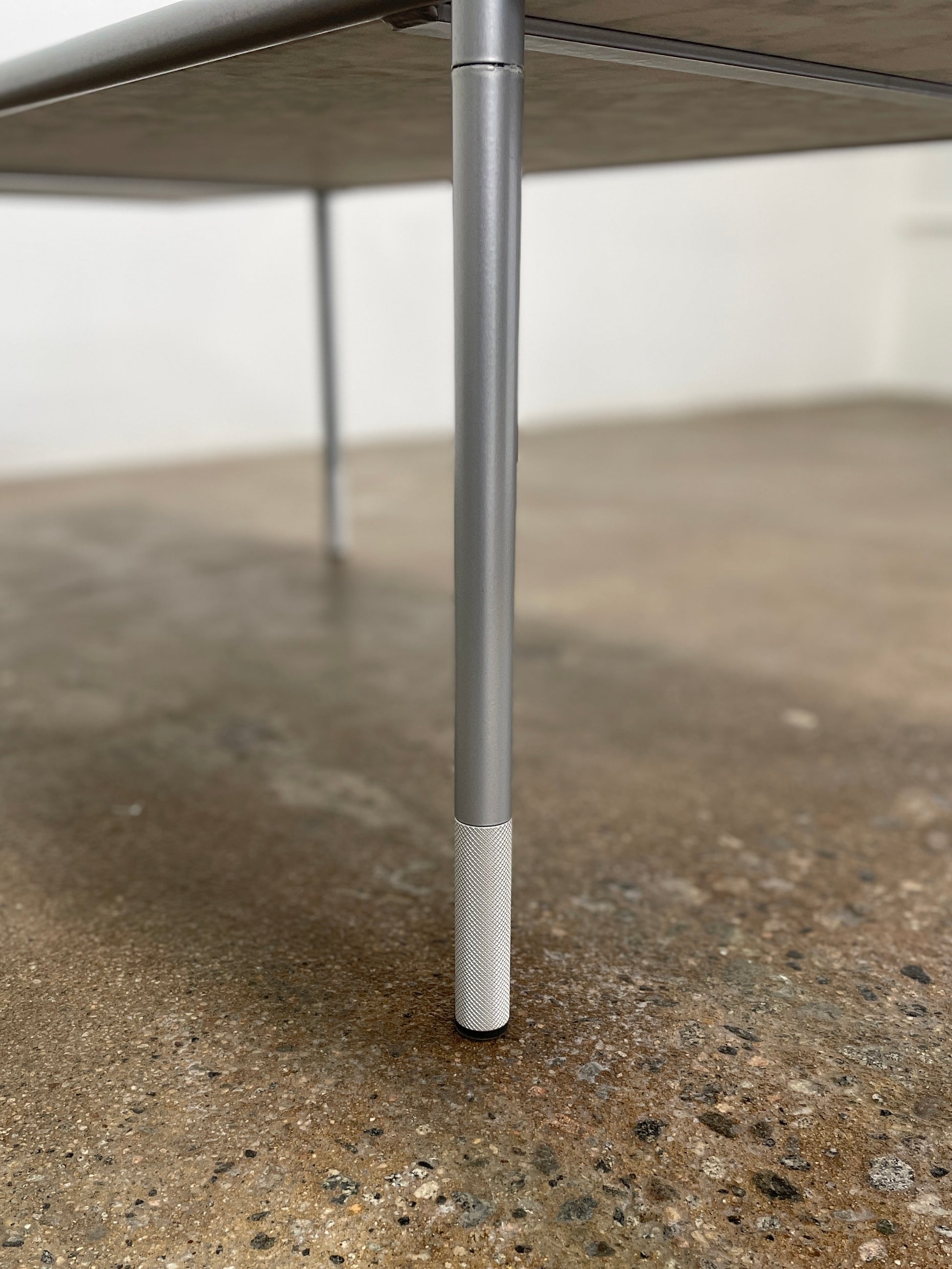 The Artelano Carrara Marble Coffee Table boasts a rectangular marble top with sleek metal legs and a central wood tray, exuding the Parisian elegance of the Artelano brand.