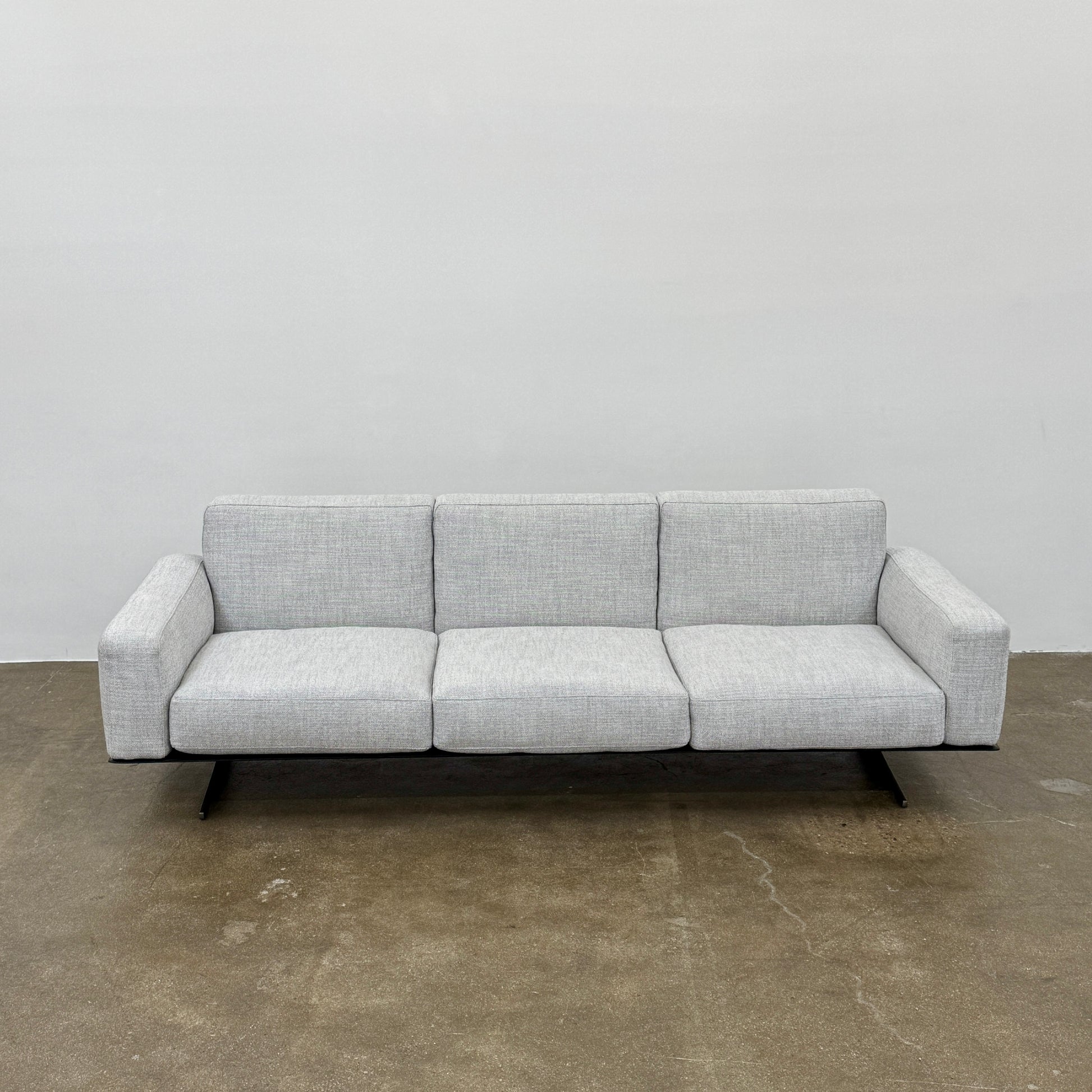 A contemporary Flexform Dream Sofa in light gray, featuring wide armrests and black metal legs, is displayed against a plain white background.