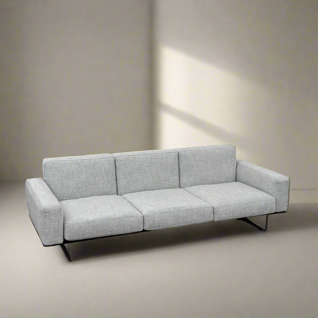 A contemporary Flexform Dream Sofa in light gray, featuring wide armrests and black metal legs, is displayed against a plain white background.