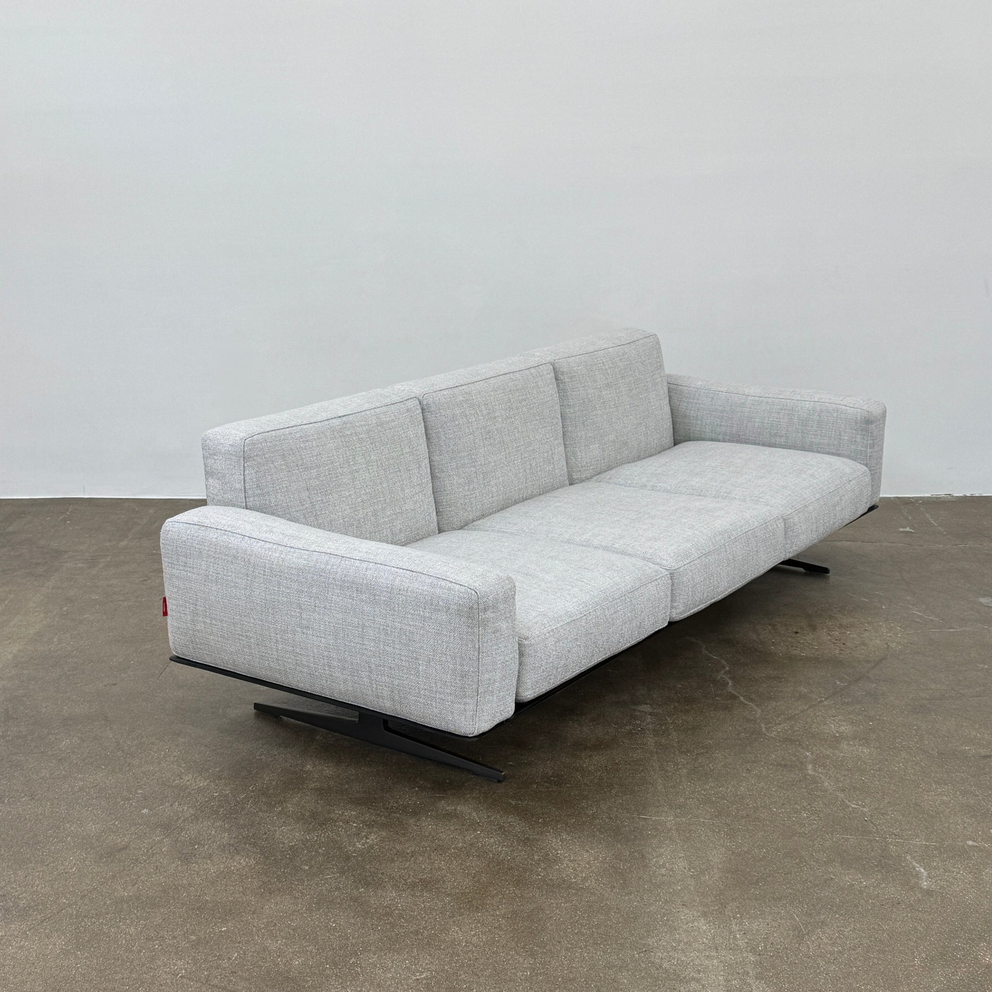 A contemporary Flexform Dream Sofa in light gray, featuring wide armrests and black metal legs, is displayed against a plain white background.
