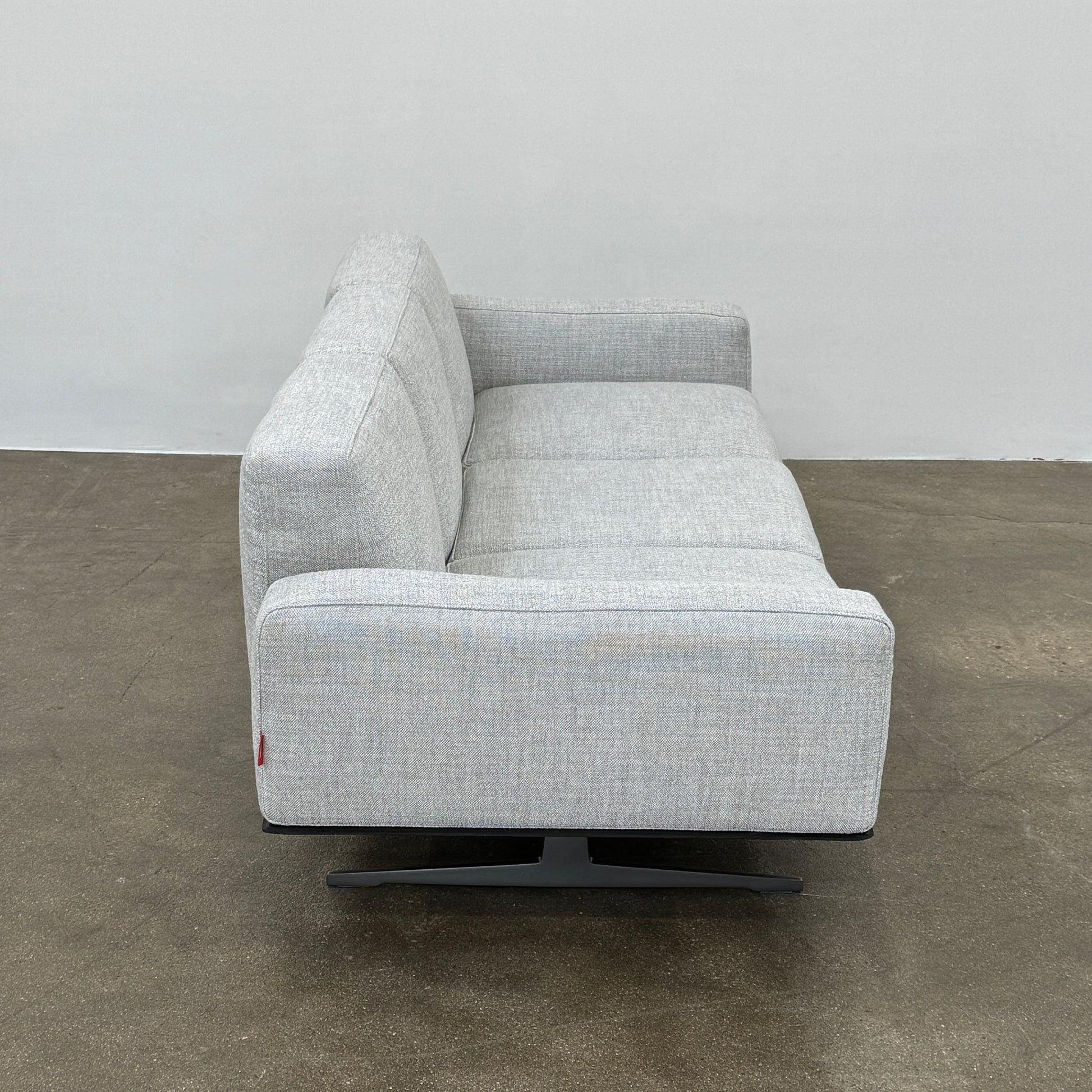 A contemporary Flexform Dream Sofa in light gray, featuring wide armrests and black metal legs, is displayed against a plain white background.