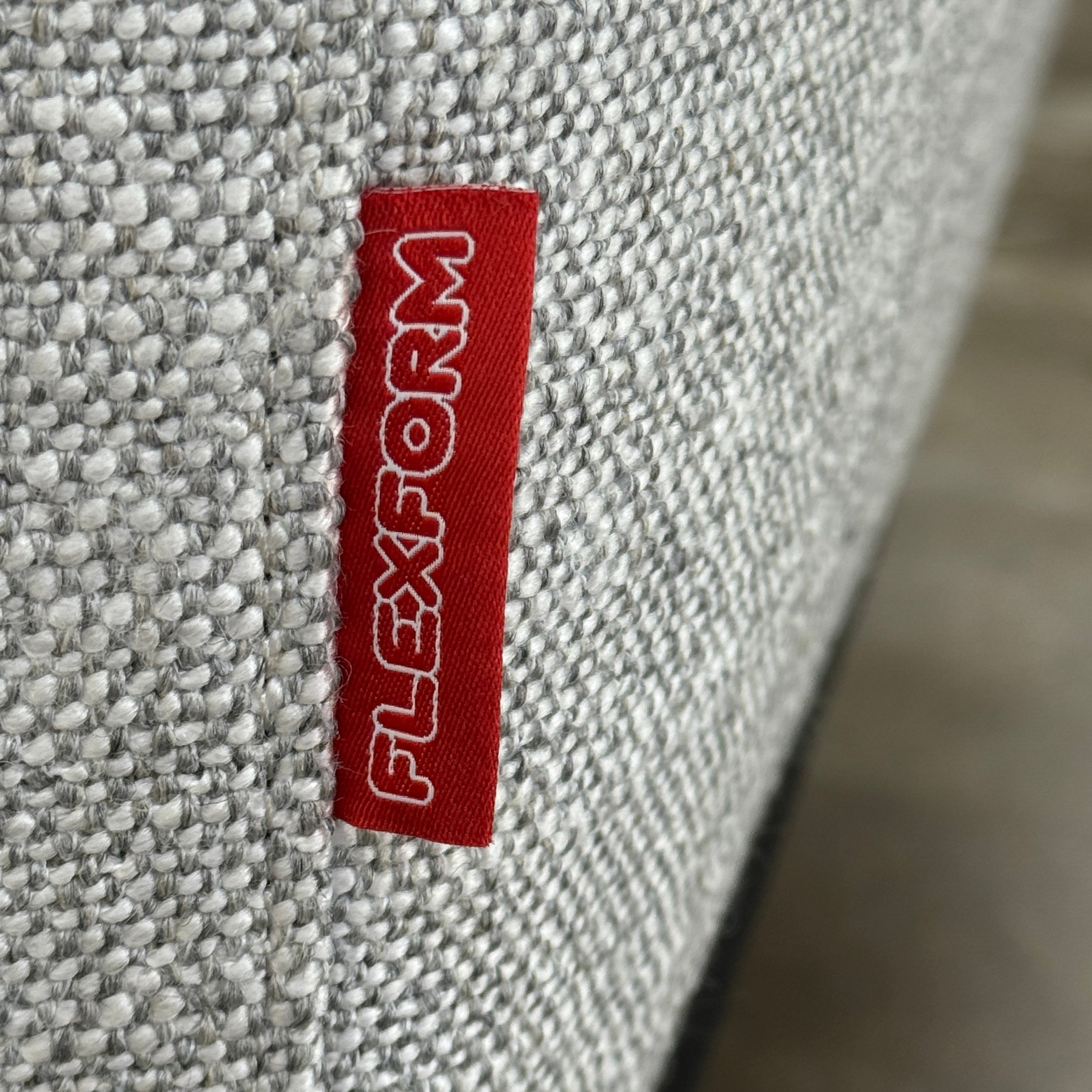 A contemporary Flexform Dream Sofa in light gray, featuring wide armrests and black metal legs, is displayed against a plain white background.