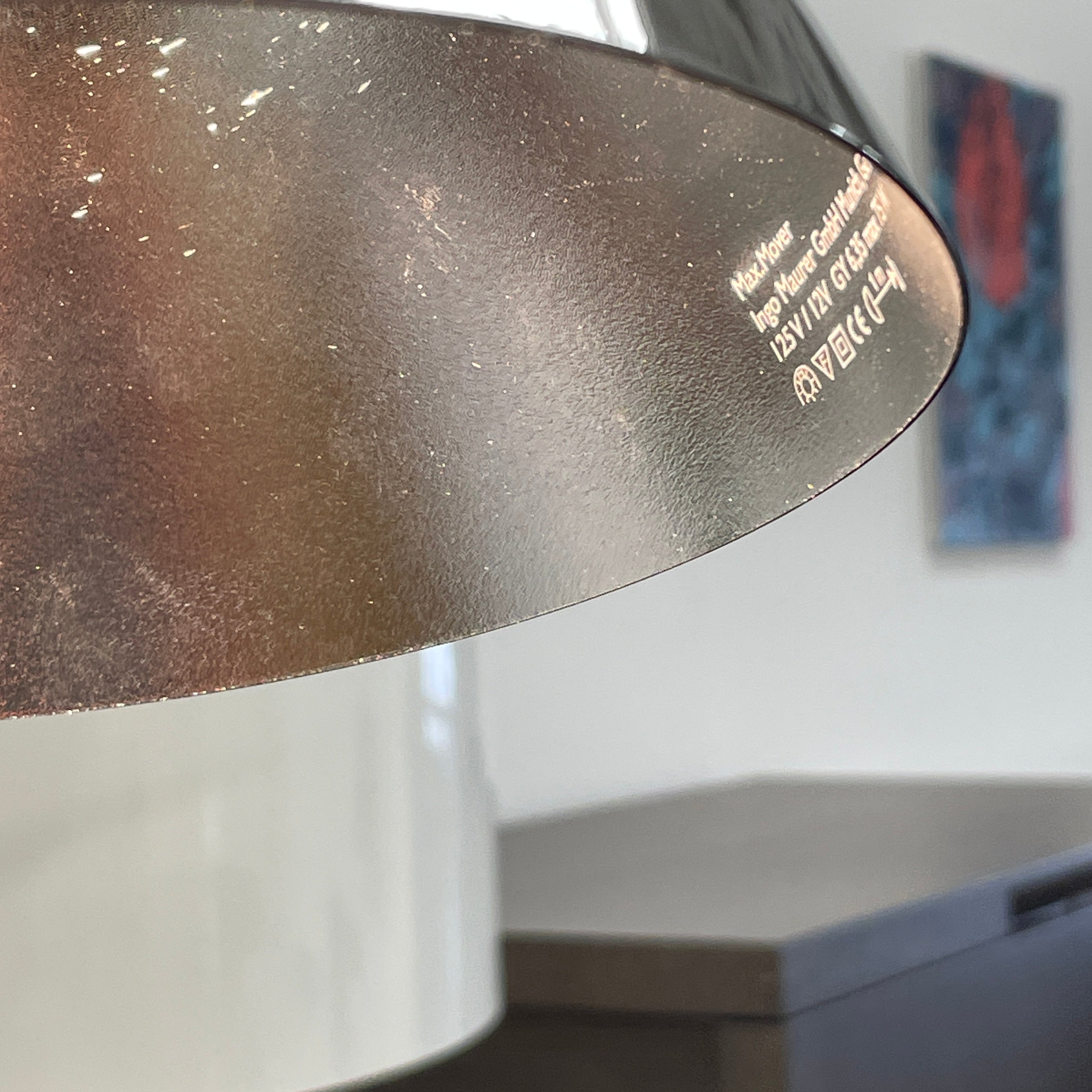 The Ingo Maurer Max Mover Wall Light by Ingo Maurer is a contemporary fixture with an adjustable telescopic rod, sleek black arm, and aluminum reflector in a dome-shaped shade set against a light grey backdrop.