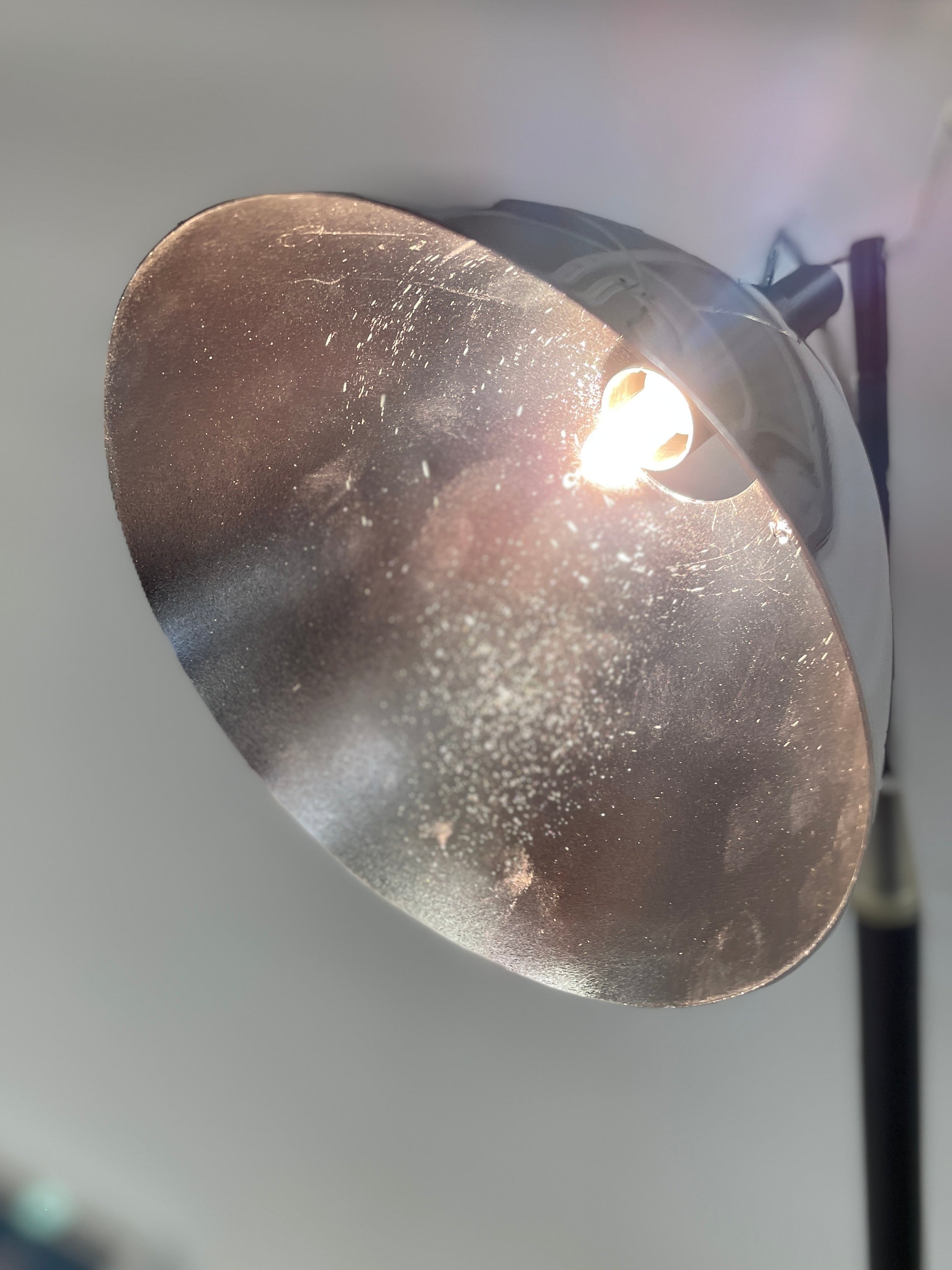 The Ingo Maurer Max Mover Wall Light by Ingo Maurer is a contemporary fixture with an adjustable telescopic rod, sleek black arm, and aluminum reflector in a dome-shaped shade set against a light grey backdrop.