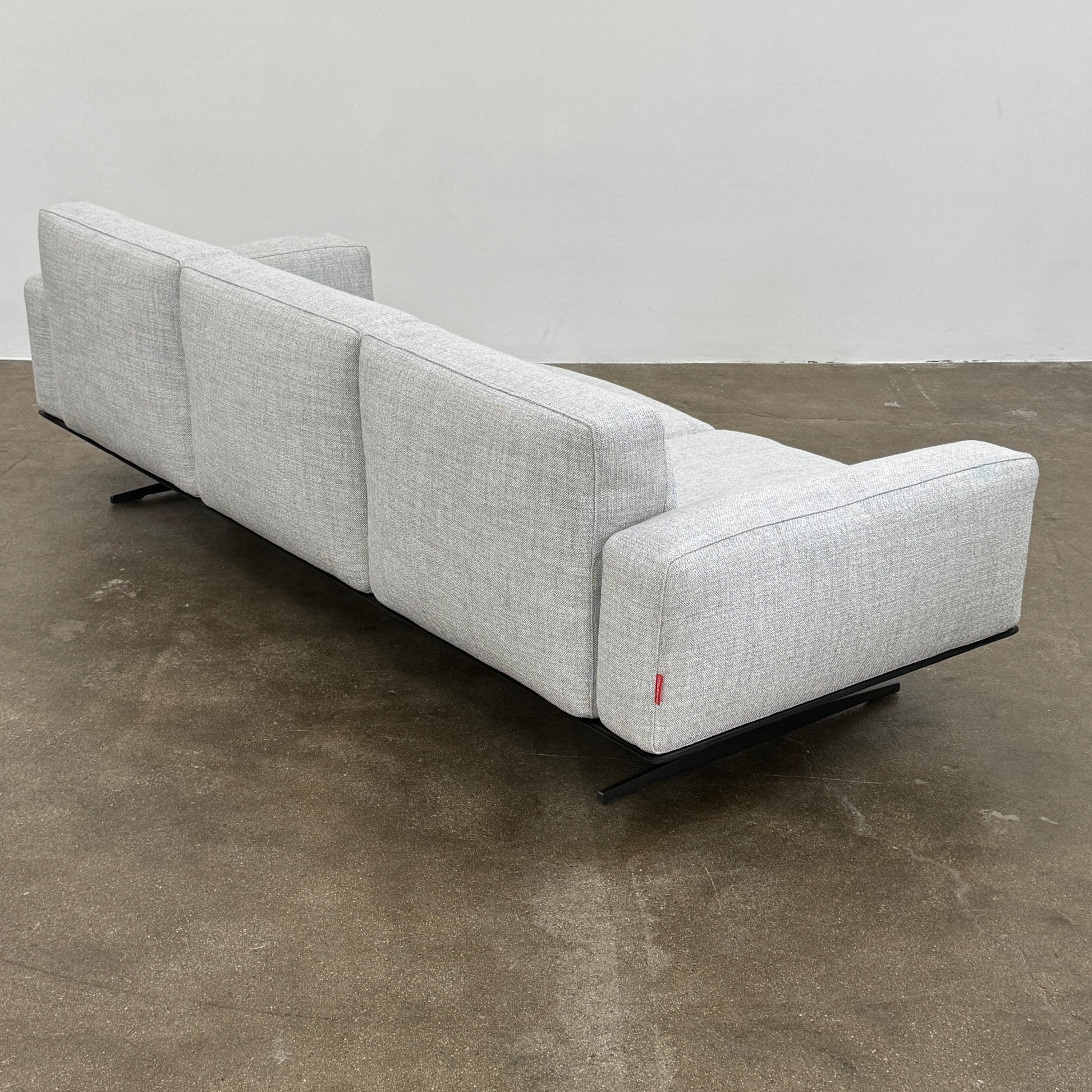 A contemporary Flexform Dream Sofa in light gray, featuring wide armrests and black metal legs, is displayed against a plain white background.