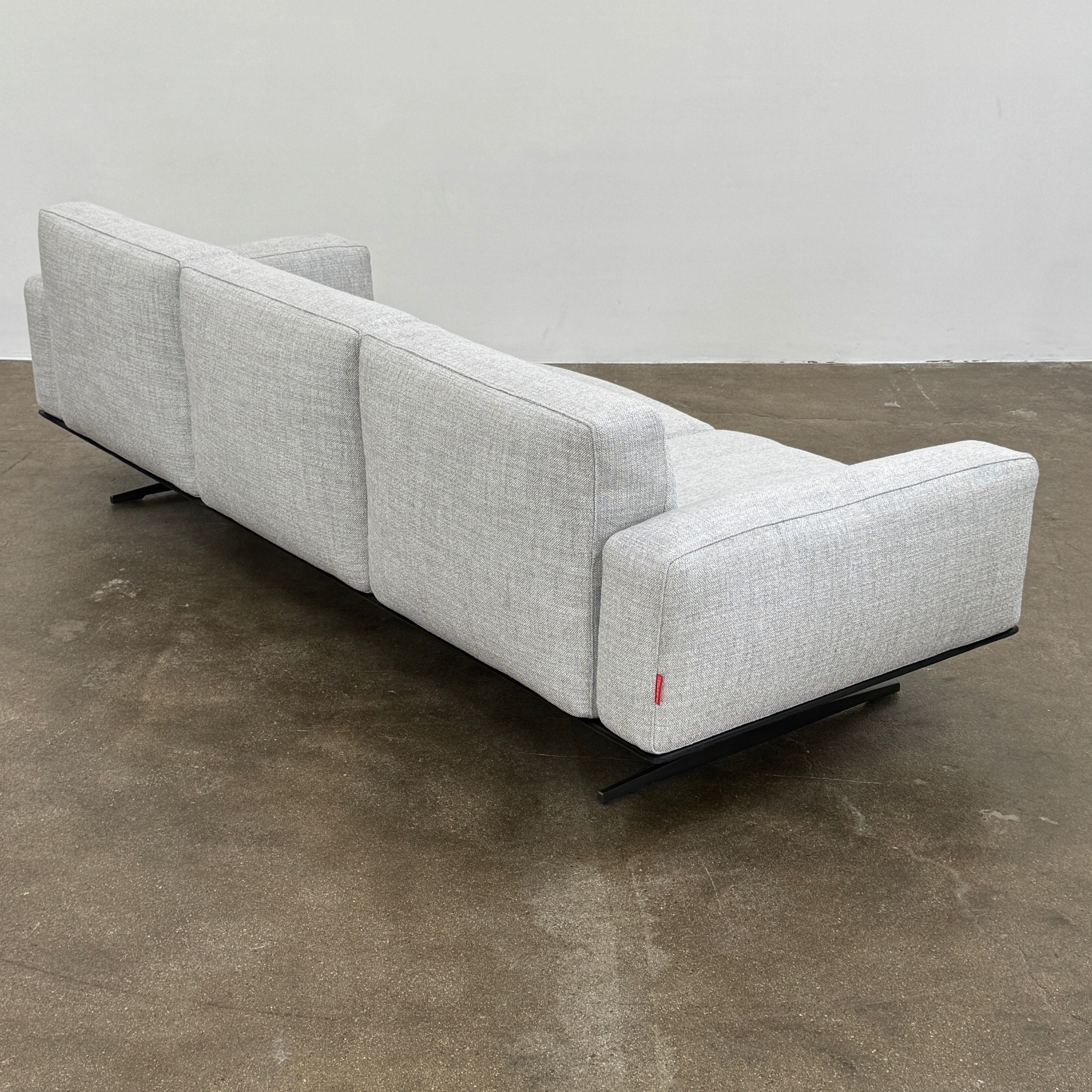 A contemporary Flexform Dream Sofa in light gray, featuring wide armrests and black metal legs, is displayed against a plain white background.
