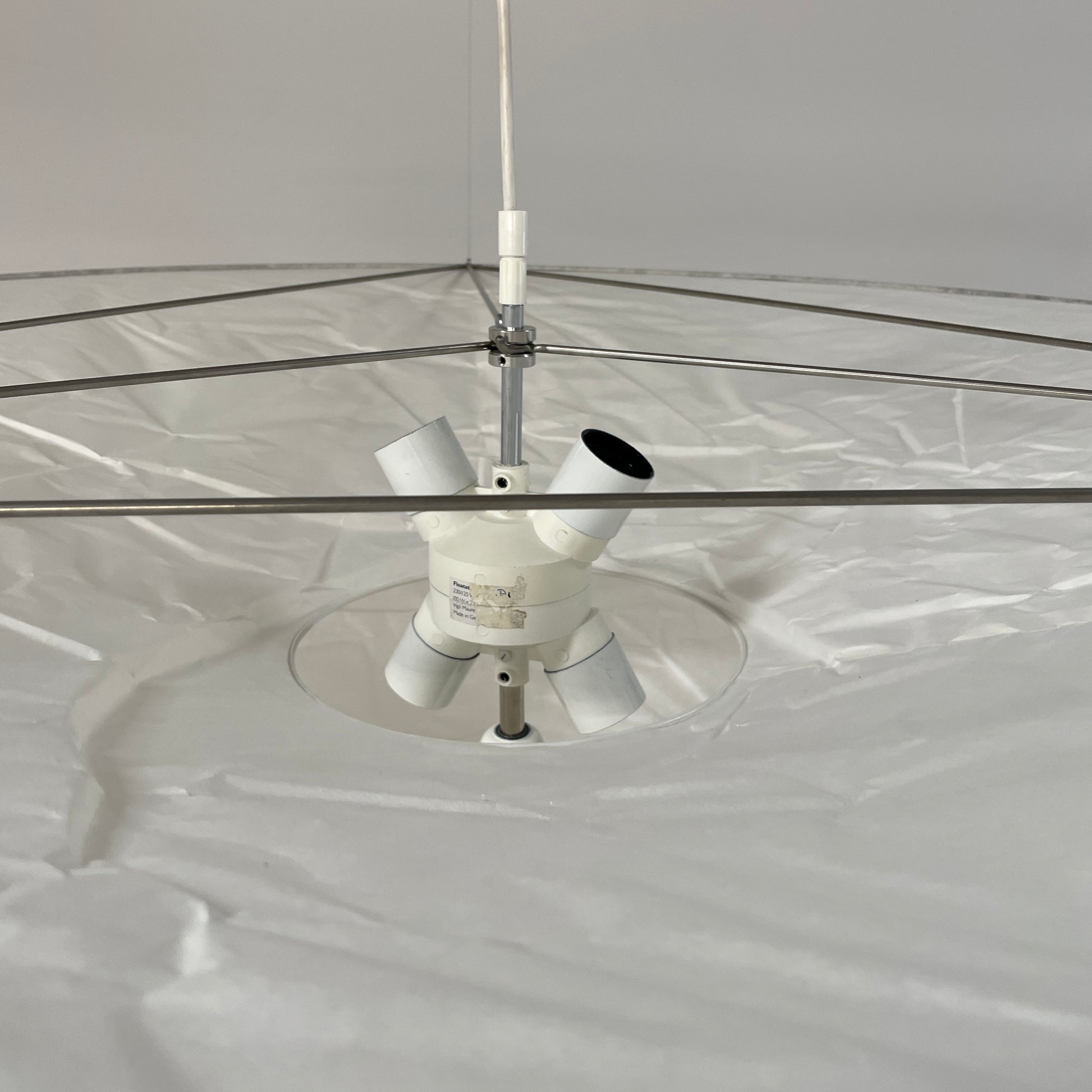 The Ingo Maurer Floatation Suspension Light Medium Size is a modern chandelier with a red ring accent and three overlapping circular discs, showcasing Ingo Maurer's artistry with its elegant and innovative design, suspended elegantly by wires.