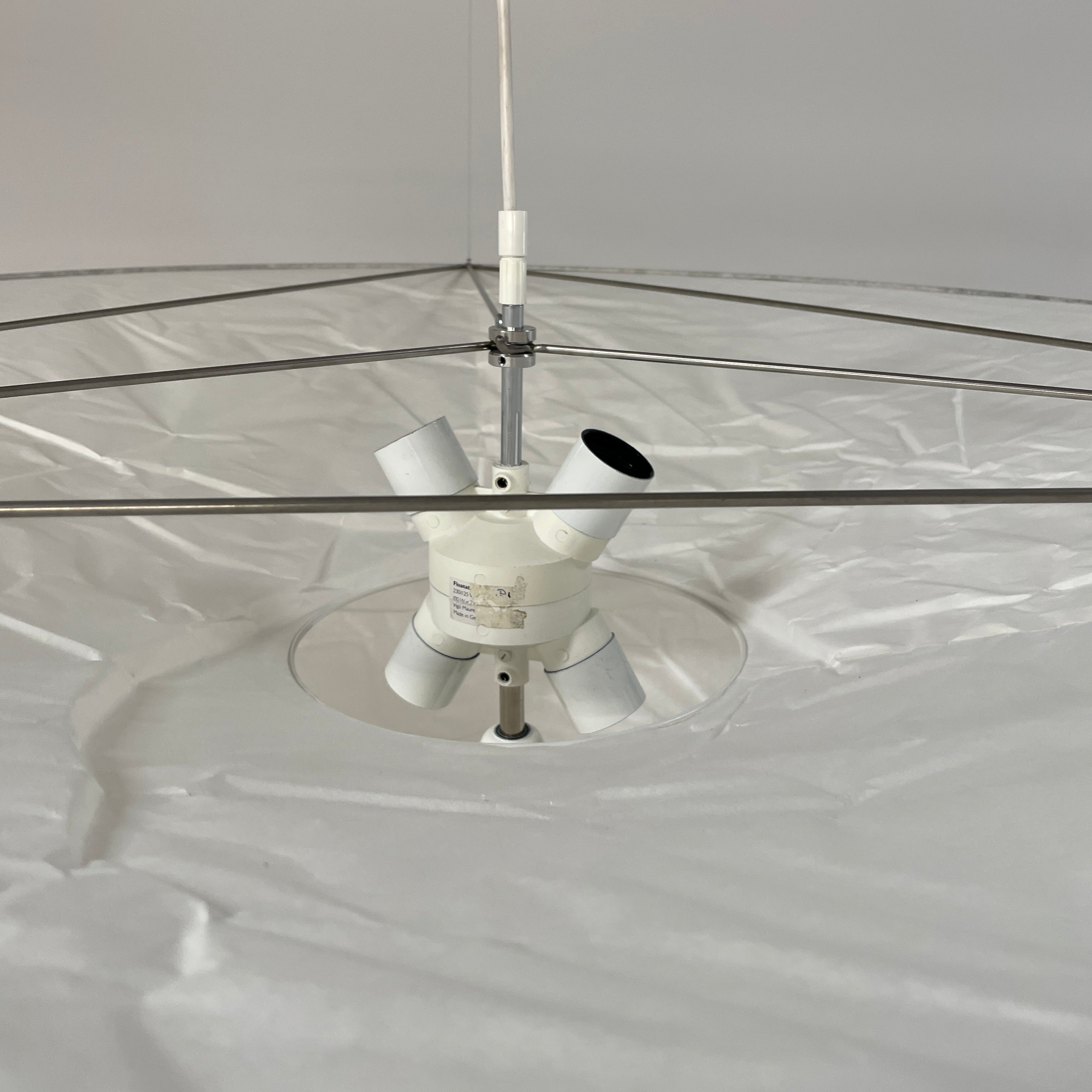 The Ingo Maurer Floatation Suspension Light Medium Size is a modern chandelier with a red ring accent and three overlapping circular discs, showcasing Ingo Maurer's artistry with its elegant and innovative design, suspended elegantly by wires.