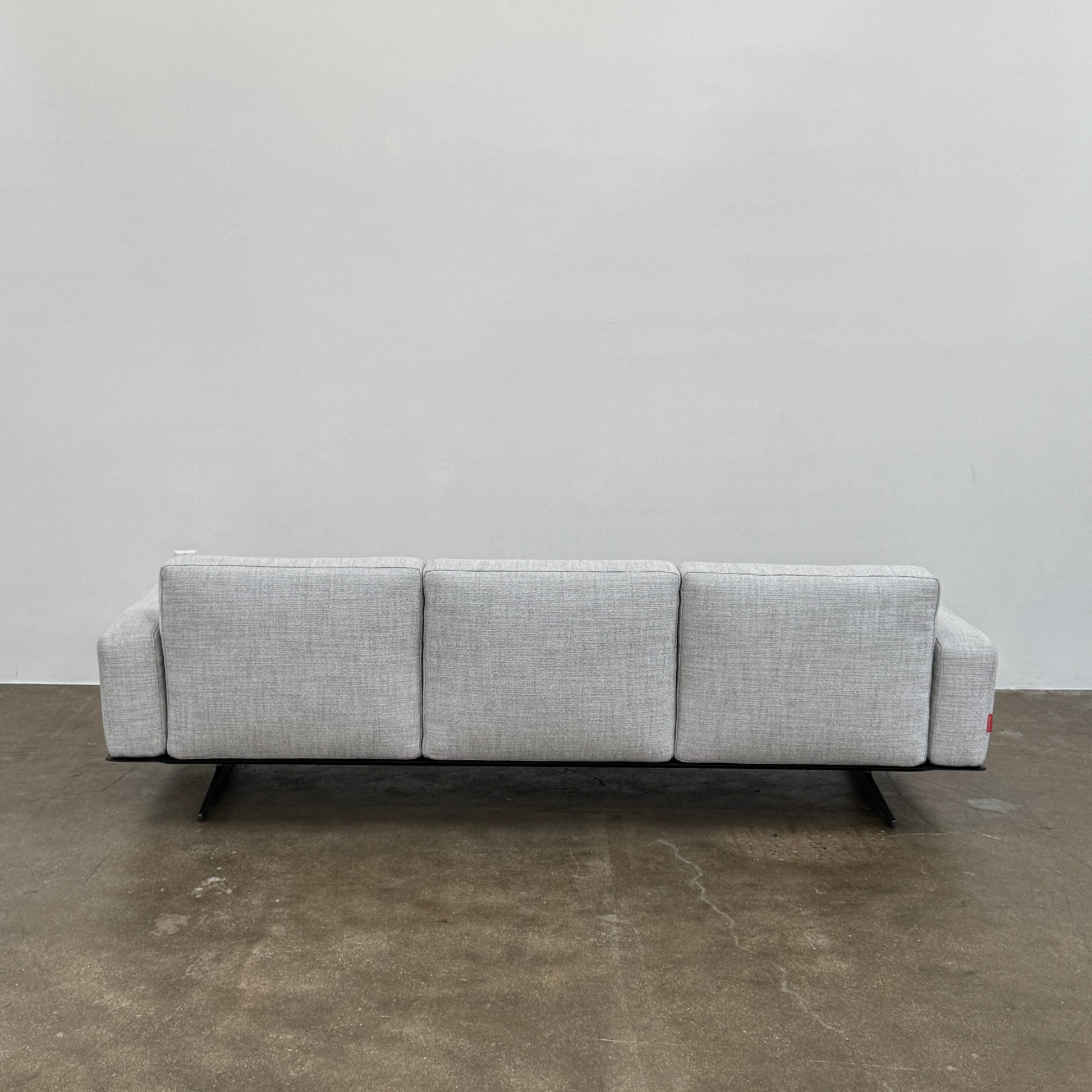 A contemporary Flexform Dream Sofa in light gray, featuring wide armrests and black metal legs, is displayed against a plain white background.