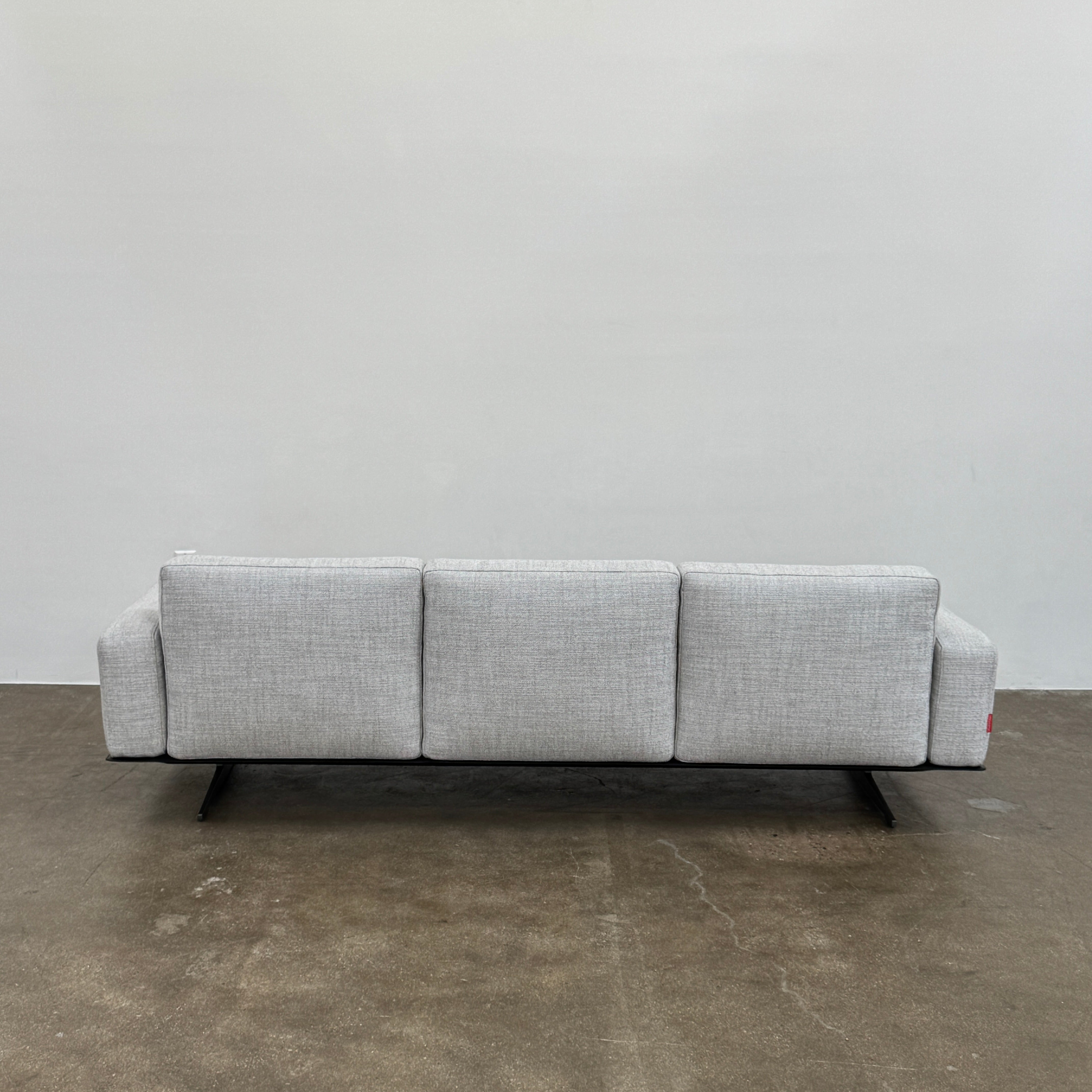 A contemporary Flexform Dream Sofa in light gray, featuring wide armrests and black metal legs, is displayed against a plain white background.