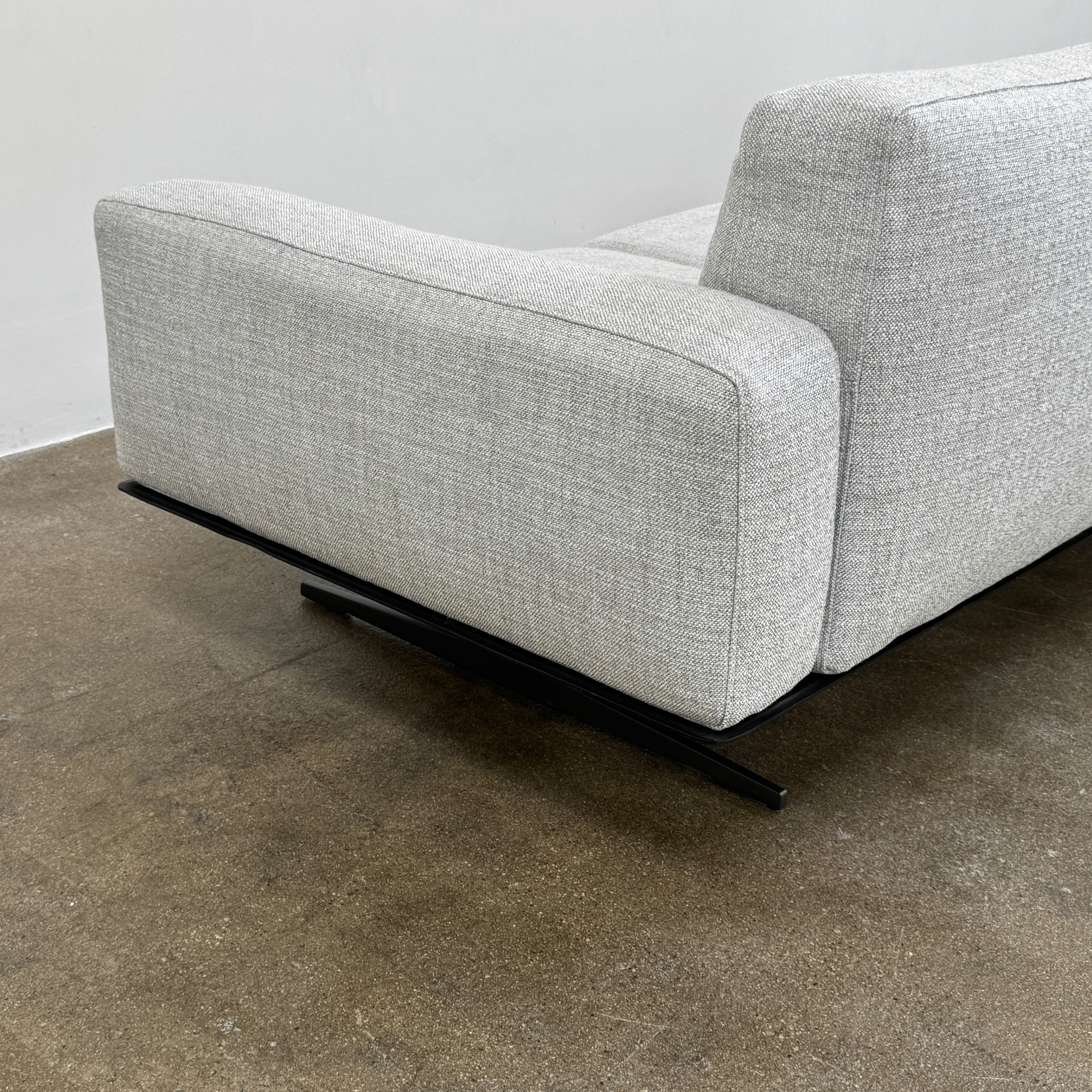 A contemporary Flexform Dream Sofa in light gray, featuring wide armrests and black metal legs, is displayed against a plain white background.
