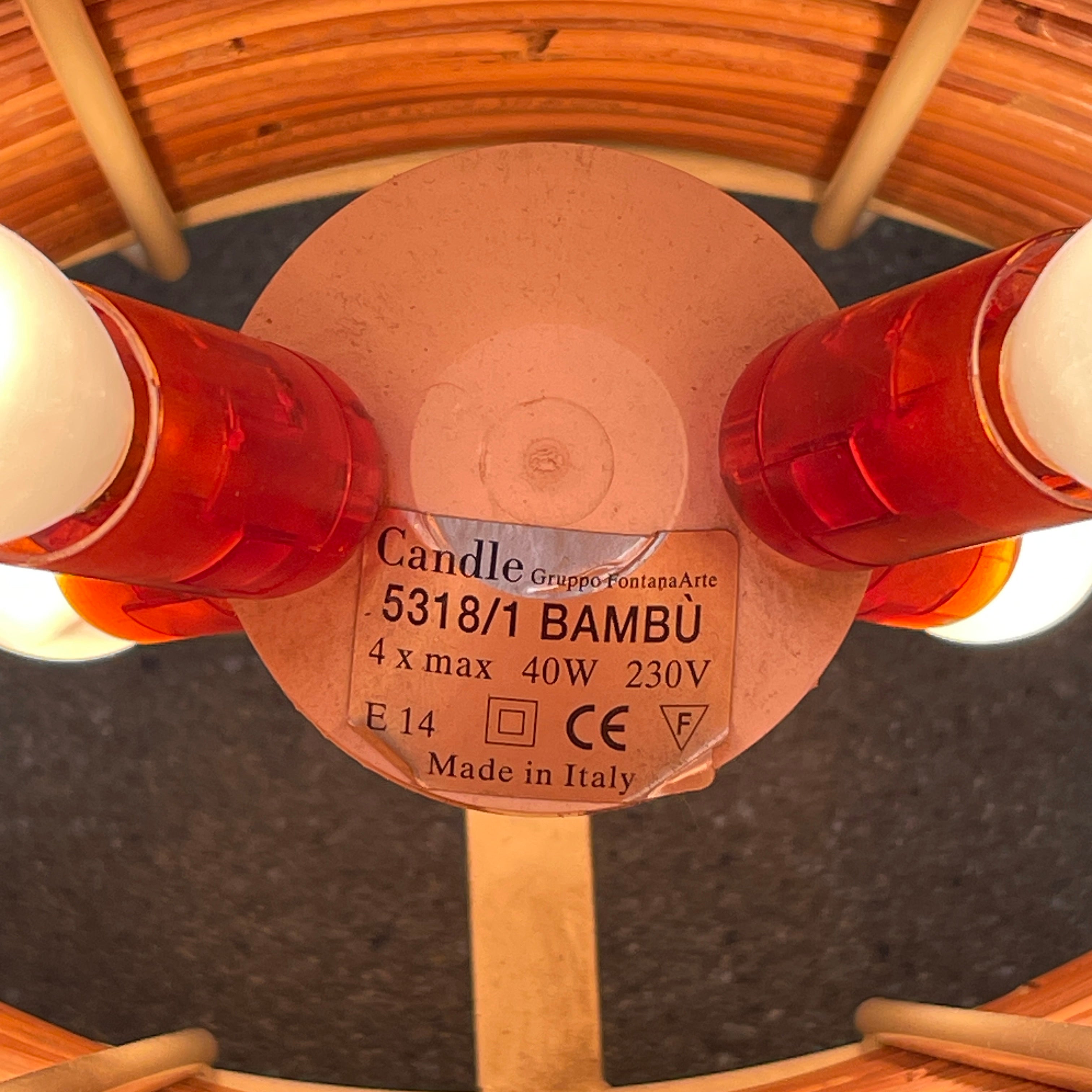 The Vintage Fontana Arte Bambú Table Light by Fontana Arte showcases a woven rattan circular shade atop a sleek white metal tripod base, making it an elegant addition to a wooden table. This lamp enhances your home's interior lighting with its natural charm and unique design.