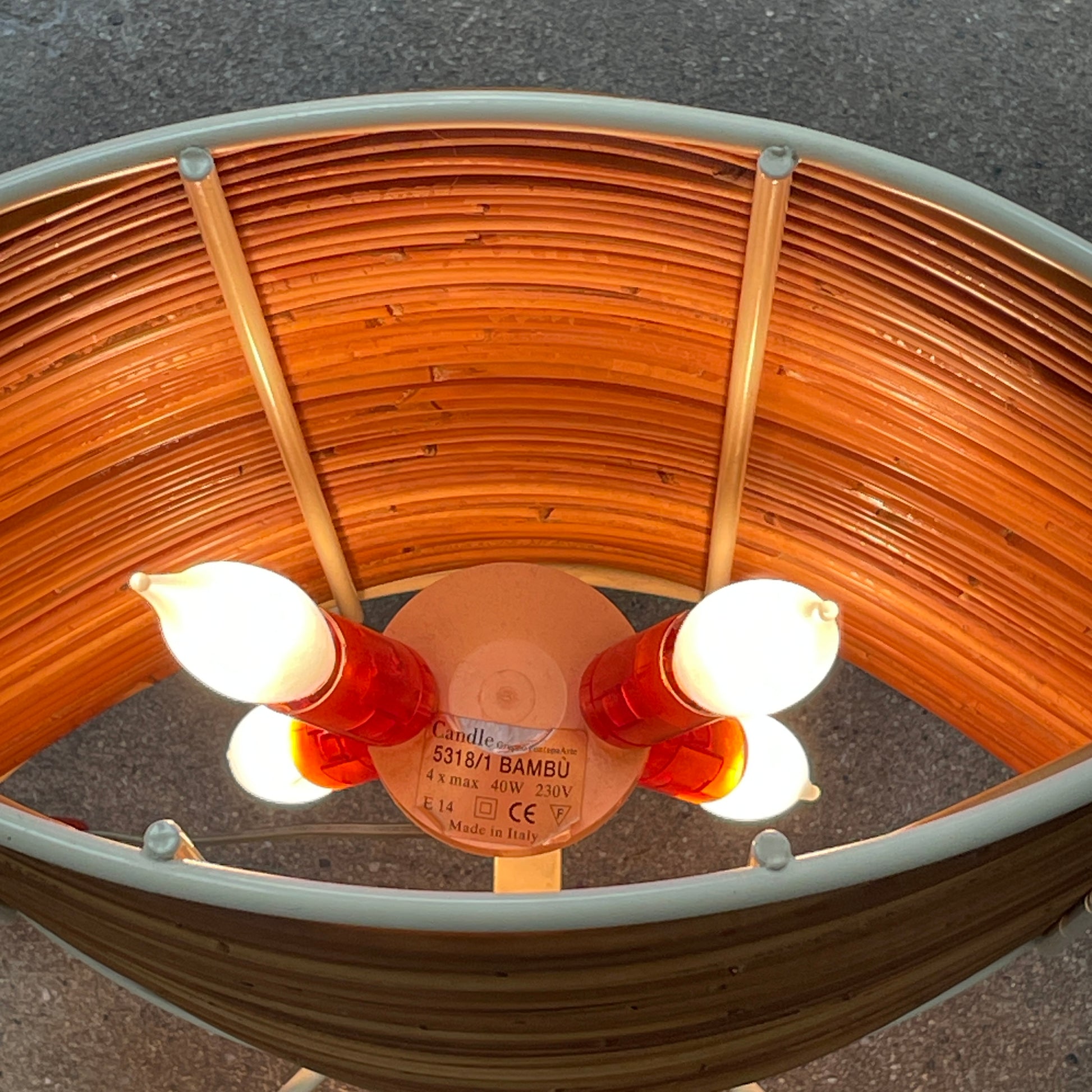 The Vintage Fontana Arte Bambú Table Light by Fontana Arte showcases a woven rattan circular shade atop a sleek white metal tripod base, making it an elegant addition to a wooden table. This lamp enhances your home's interior lighting with its natural charm and unique design.