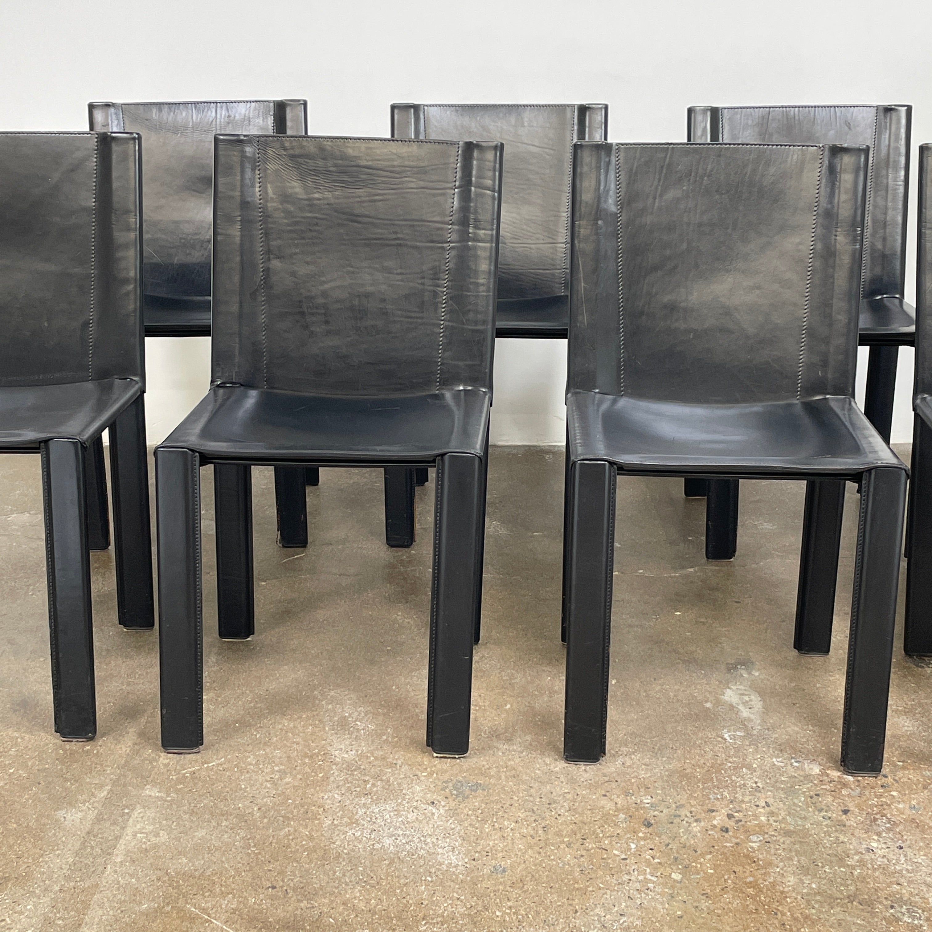 Eight Vintage Matteo Grassi 'Coral' dining chairs, showcasing a sleek black finish, are arranged in two rows on a pristine white background.