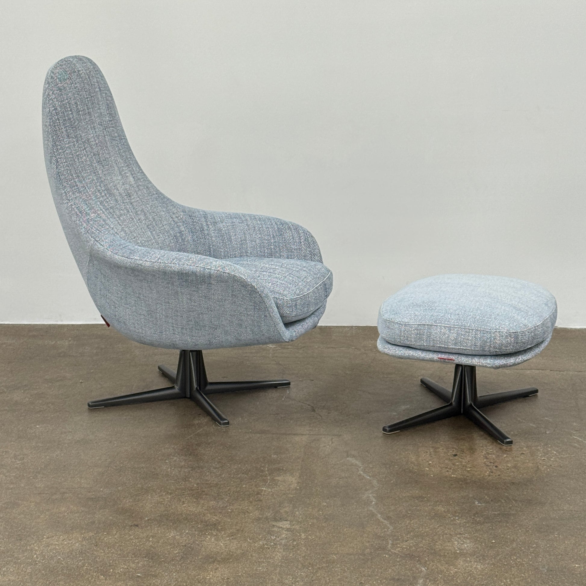 The Flexform Marlon Swivel Armchair and Ottoman, available with two covers, feature ergonomic design and black metal bases from Flexform, shown here in a modern gray finish against a plain white background.
